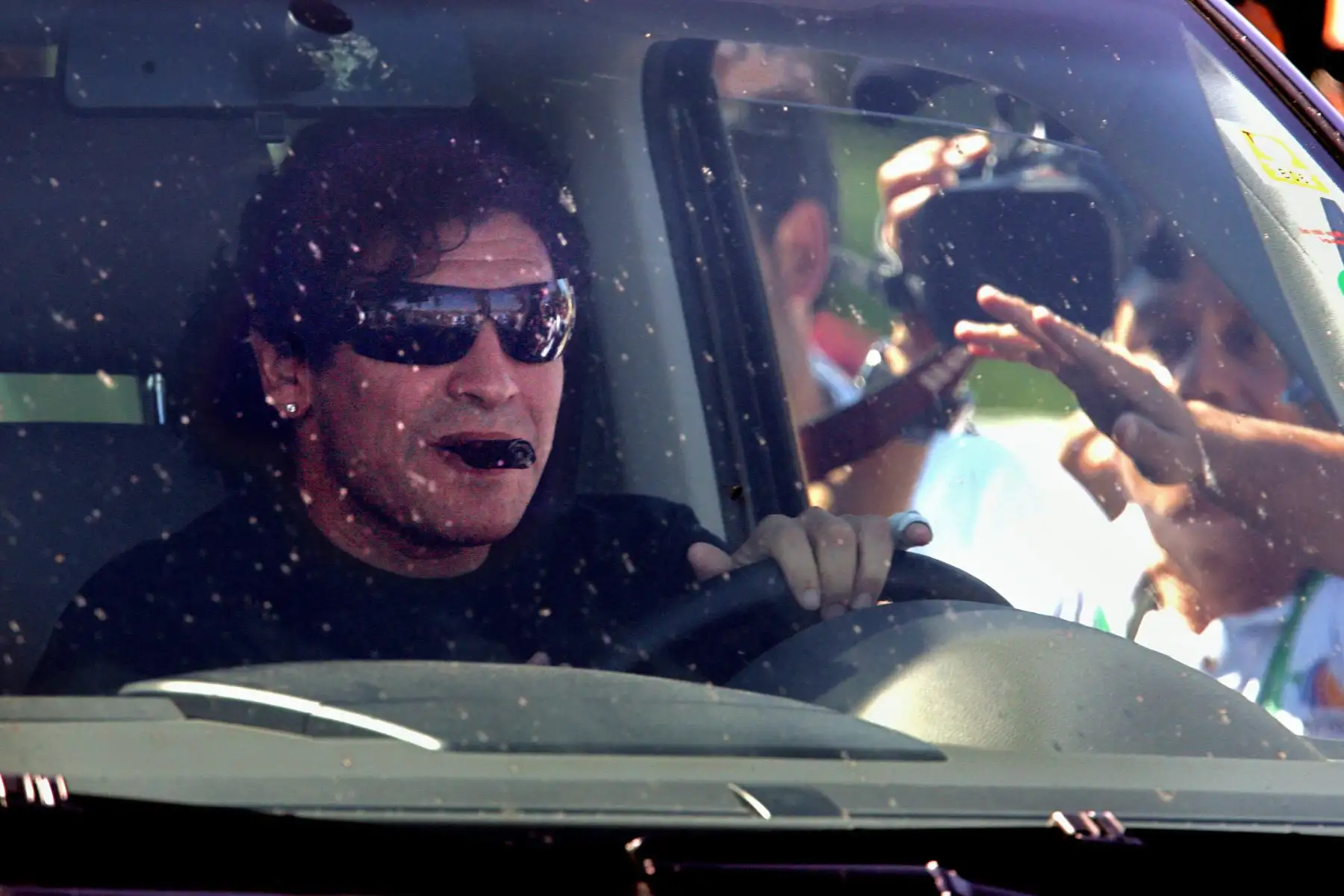 En esta foto de archivo tomada el 12 de junio de 2006, la gente saluda al astro del fútbol argentino Diego Maradona mientras se transporta en automóvil para salir del Hotel HerzogsPark en Herzogenaurach, en el sur de Alemania, durante el Mundial de Fútbol de Alemania 2006. Foto: AFP