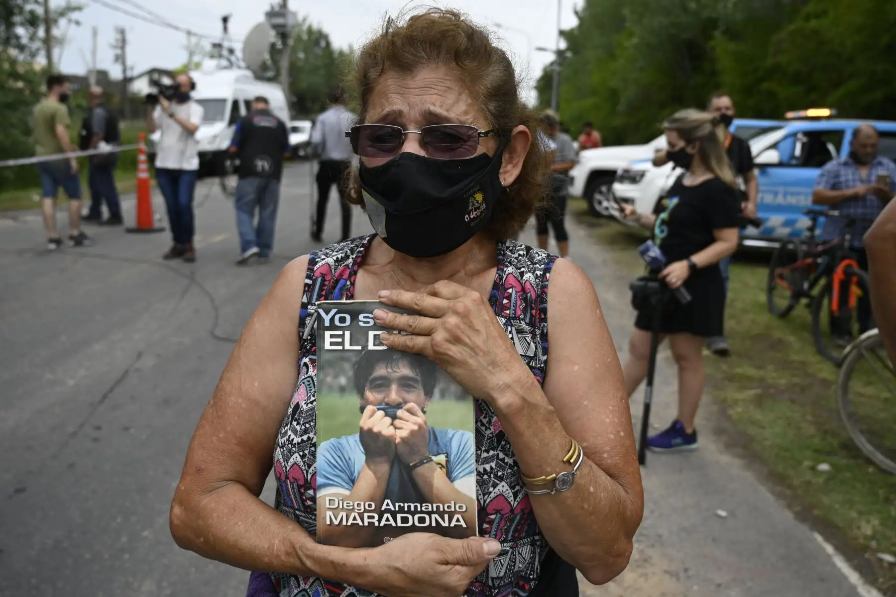 Una mujer sostiene un libro sobre la estrella del fútbol argentino Diego Maradona afuera de la comunidad cerrada donde se encuentra su casa, en Benavidez, provincia de Buenos Aires. Foto: AFP