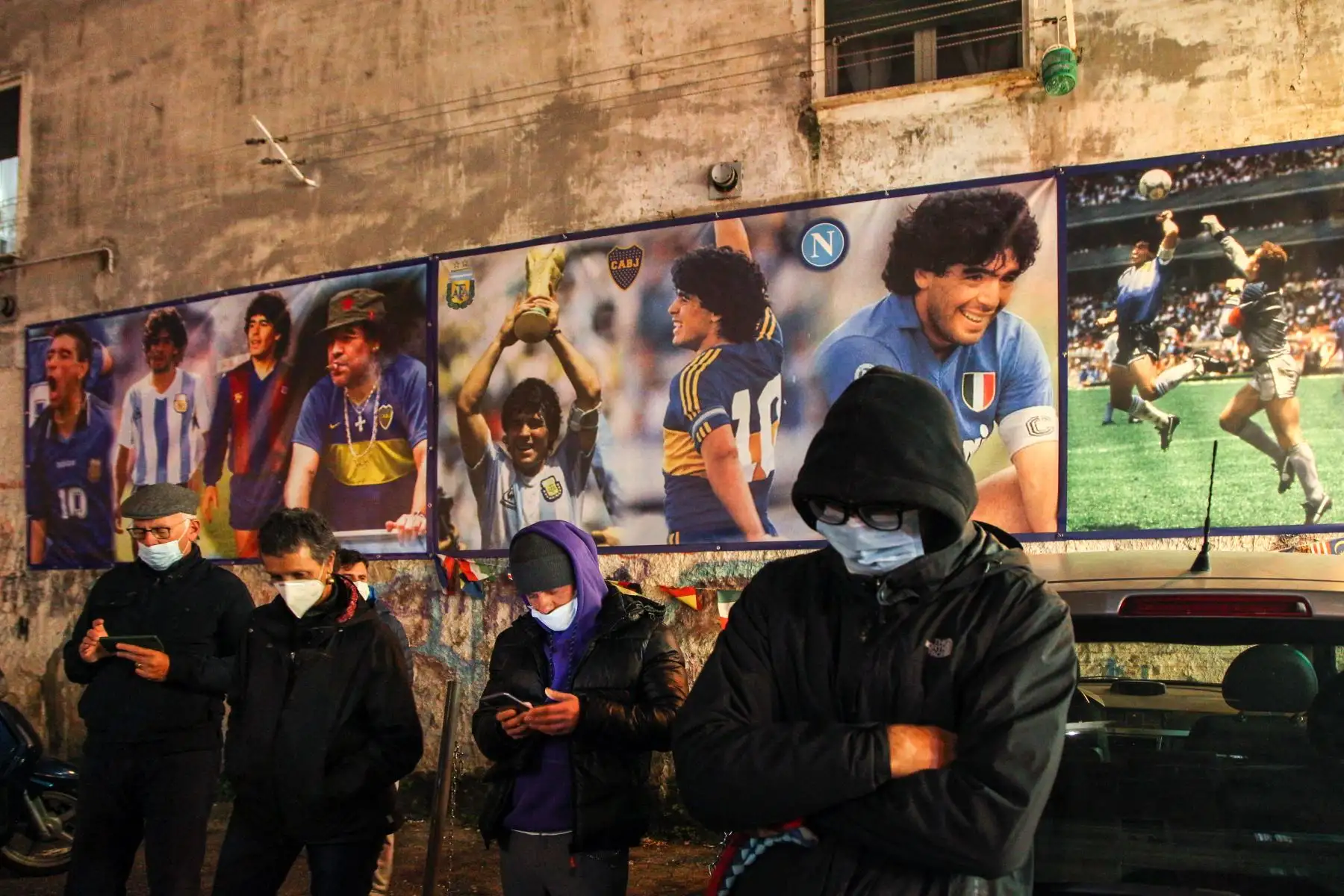 Las personas que llevan una máscara facial se paran en el llamado "Esquina Maradona" en la parte superior del Quartieri Spagnoli, en Nápoles. Foto: AFP