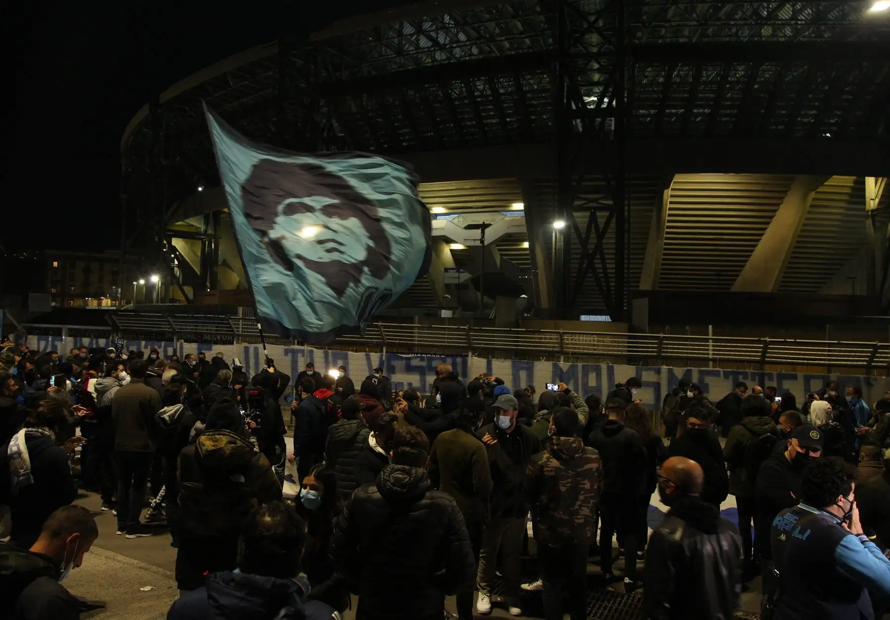 La gente se reúne en la entrada principal del estadio San Paolo en Nápoles, agitando una bandera ante la efigie de la leyenda del fútbol argentino Diego Maradona, para llorar después del anuncio de la muerte de Maradona. Foto: AFP