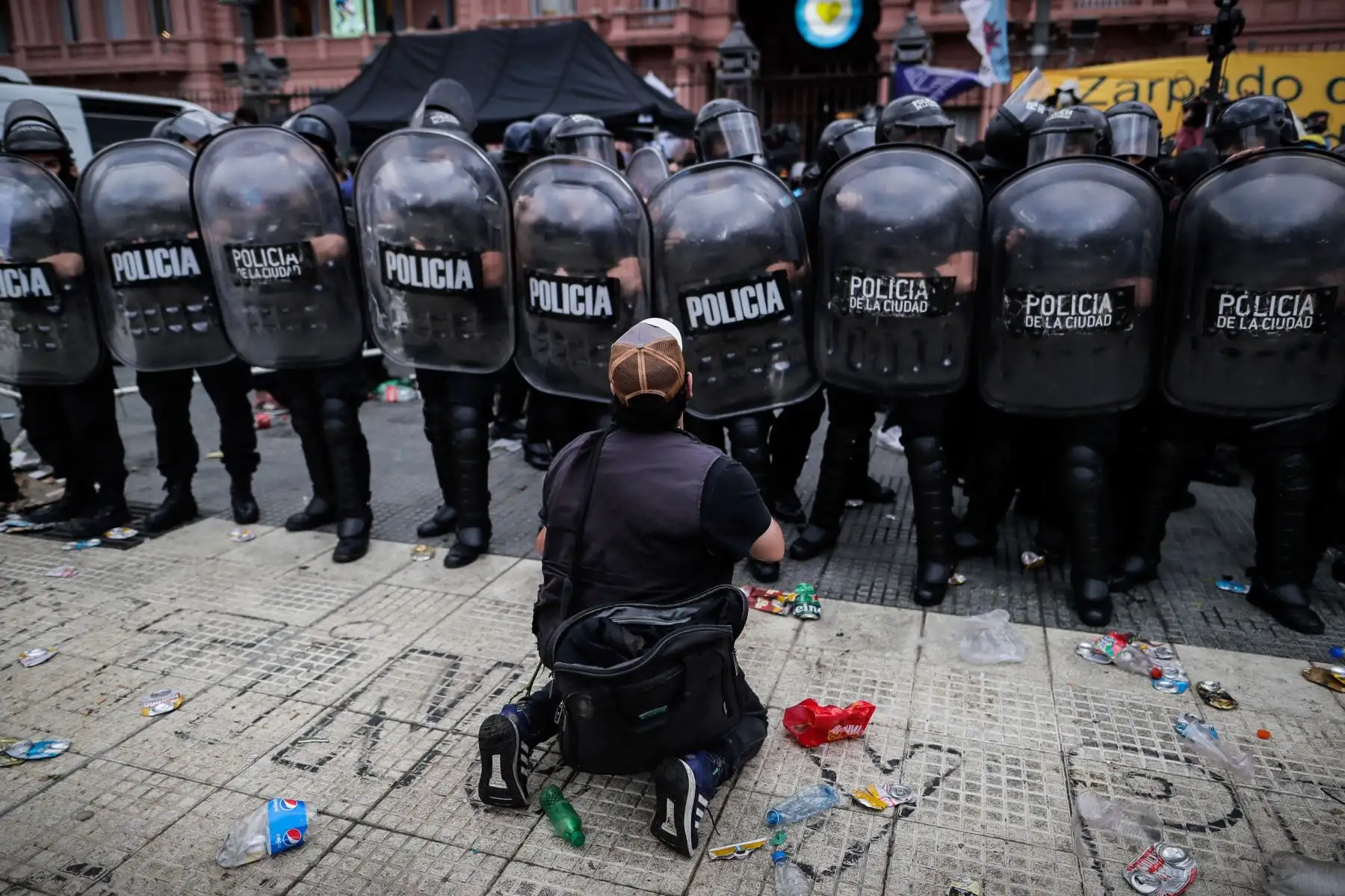 Una persona se arrodilla delante de la policía durante la espera para poder ingresar al velatorio de Diego Armando Maradona,  en la Plaza de Mayo de Buenos Aires.
Foto: EFE