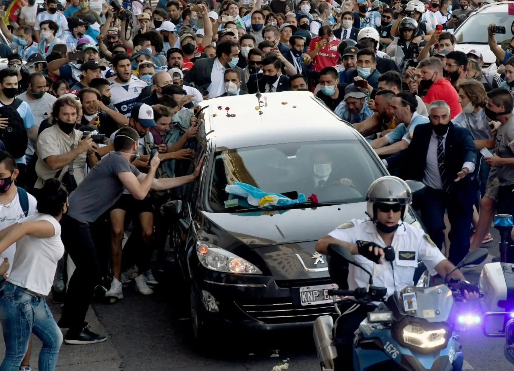 Fanáticos apiñados junto al coche fúnebre que transporta a la leyenda del fútbol argentino Diego Armando Maradona en su camino desde el palacio presidencial de la Casa Rosada al cementerio, en Buenos Aires. Foto: AFP