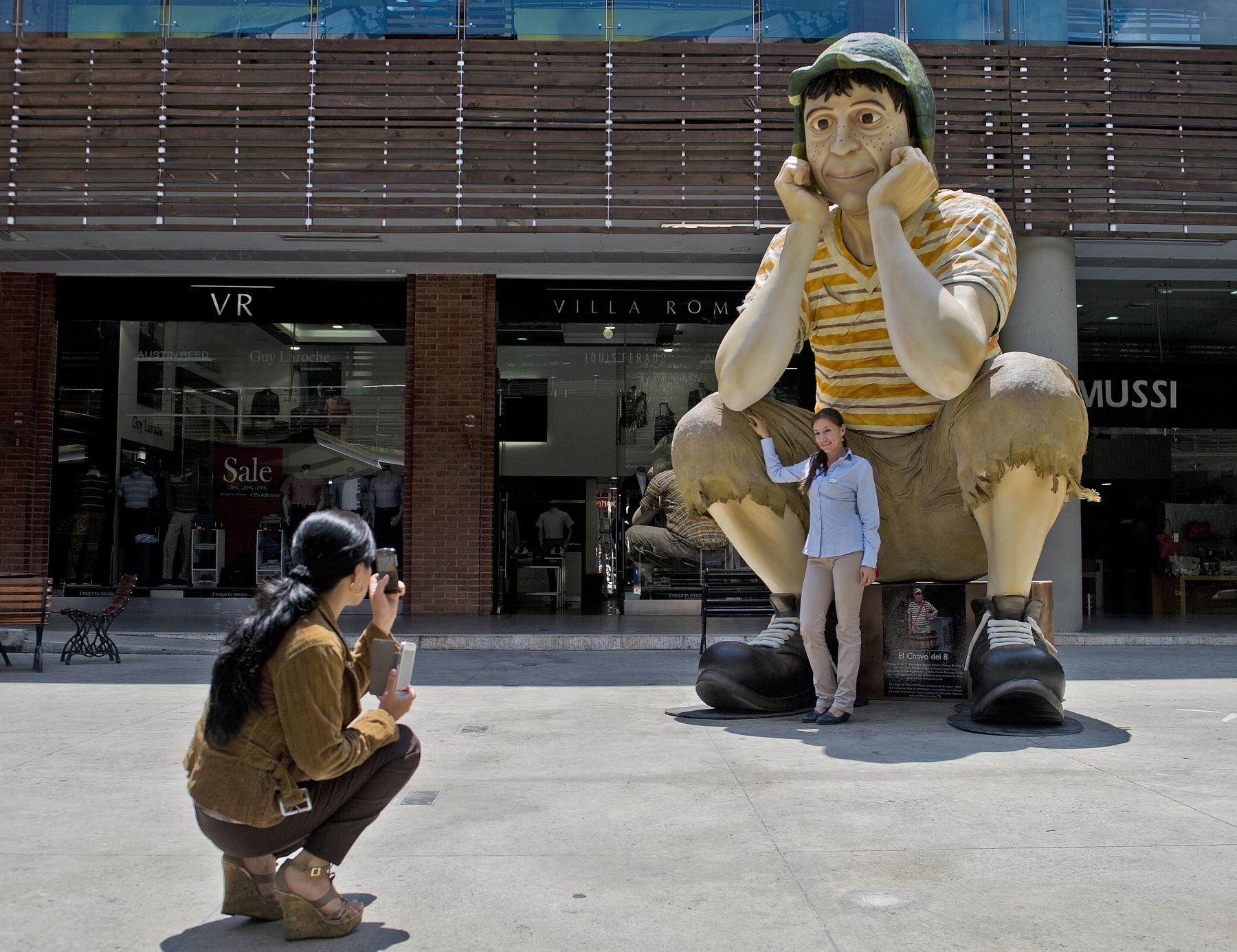 Una mujer toma una fotografía de la escultura del famoso personaje de la televisión latinoamericana "El Chavo del Ocho" exhibida en el Mall Chipichape, Colombia. Foto: AFP
