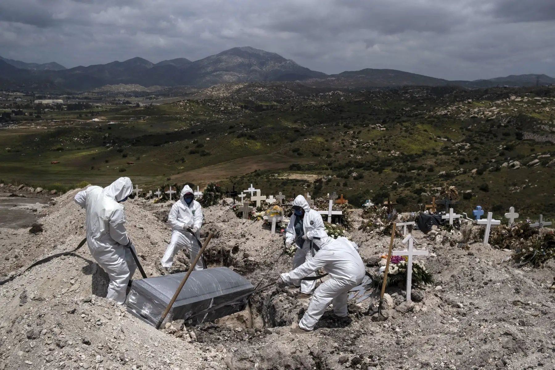 Trabajadores del cementerio con equipo de protección entierran a una víctima del coronavirus, no reclamada, en el cementerio municipal número 13 en Tijuana, México. Foto: AFP