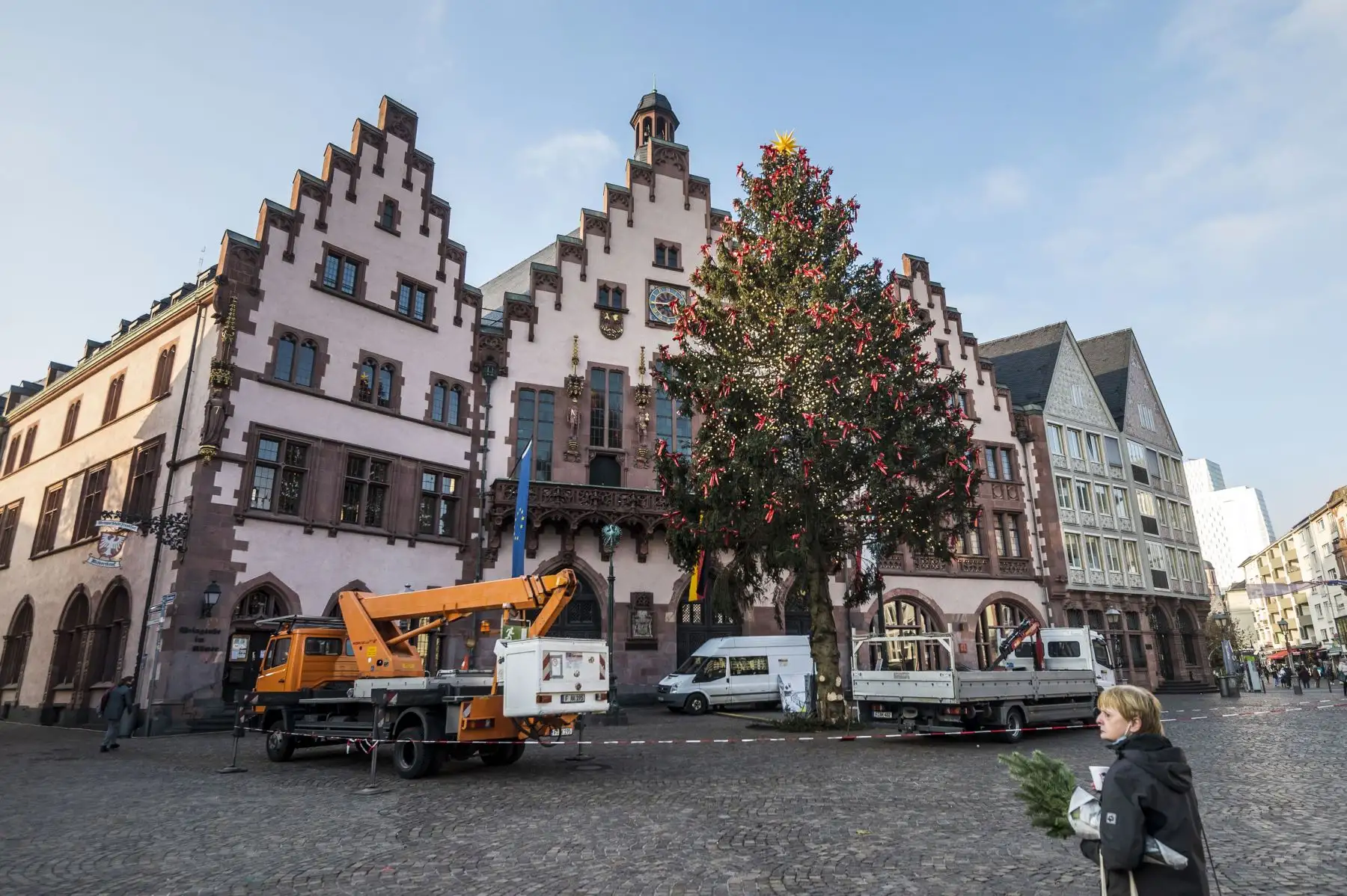 Una mujer camina cerca a un tradicional árbol de Navidad que se está instalando en el emblemático Roemer Place de Frankfurt, Alemania, en medio de la nueva pandemia de coronavirus. Foto: AFP