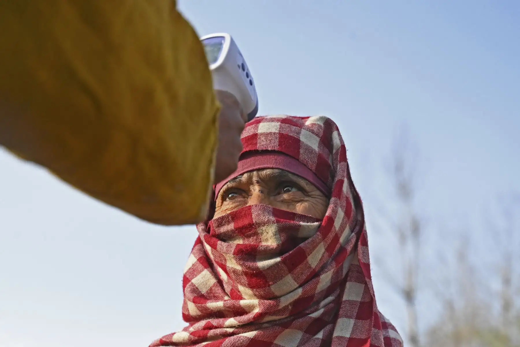 Un trabajador de la salud controla la temperatura corporal de un votante como medida preventiva contra el coronavirus, distrito de Budgam, India. Foto: AFP