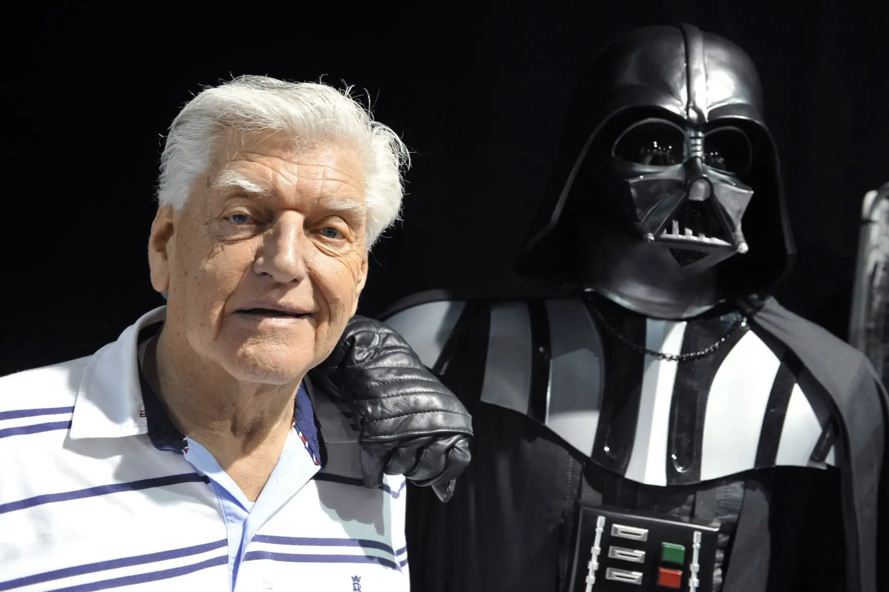 El actor inglés David Prowse quien interpretó al personaje de Darth Vader en la primera trilogía de Star Wars, posa con un fan vestido de este personaje durante una convención, el 27 de abril de 2013, en Cusset. Foto: AFP