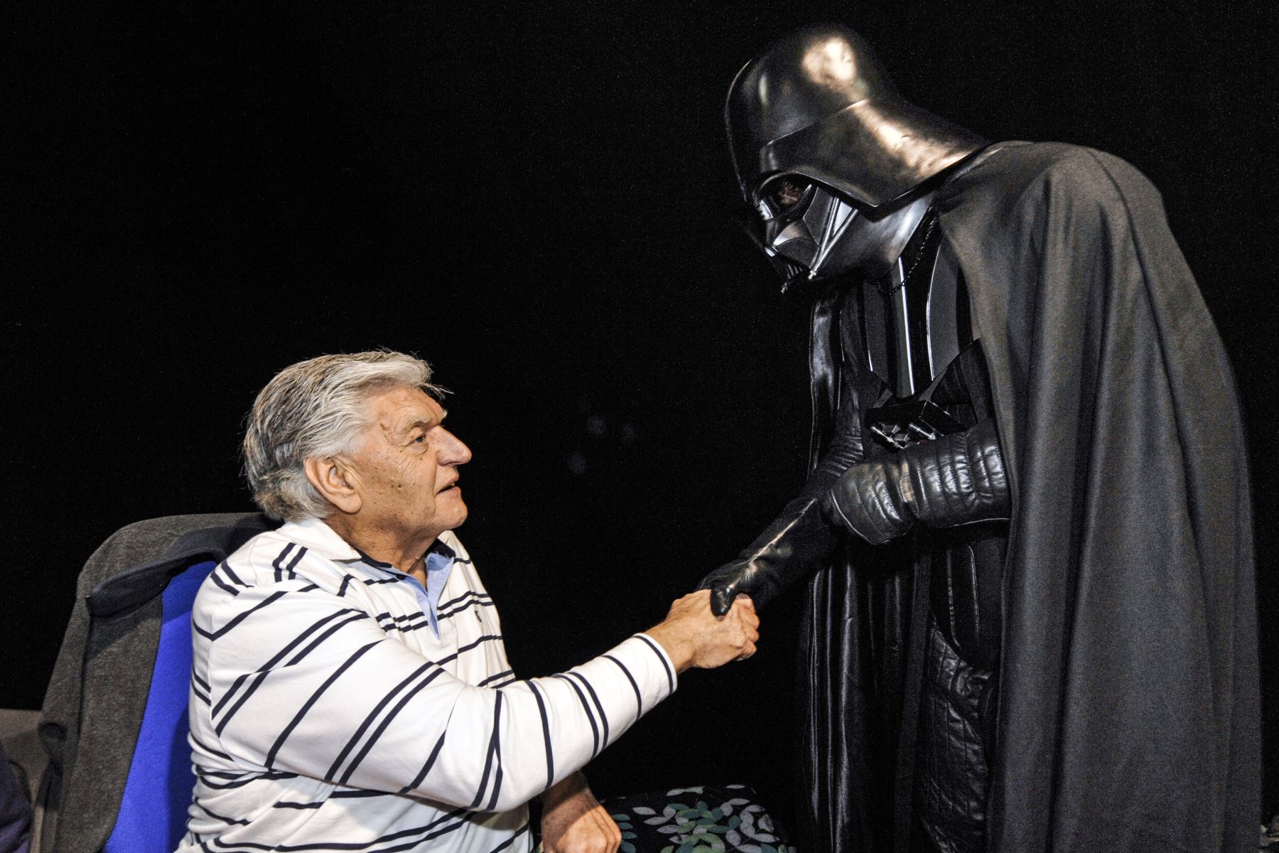 El actor inglés David Prowse quien interpretó al personaje de Darth Vader en la primera trilogía de Star Wars, le estrecha la mano a un fan vestido con un disfraz de este personaje, el 27 de abril de 2013, en Cusset. Foto: AFP