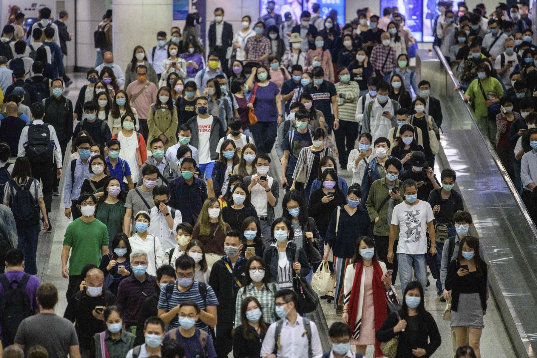 Los viajeros con mascarillas caminan en una estación de metro MTR en medio de la pandemia del coronavirus, en Hong Kong. Foto: AFP