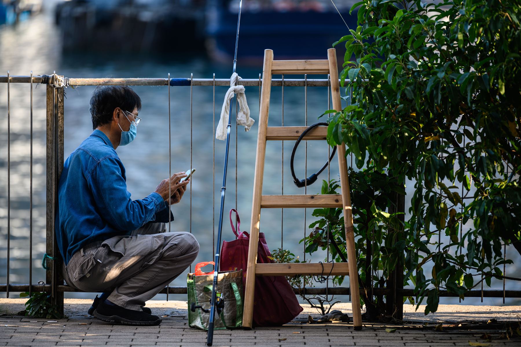 Un pescador espera y utiliza su celular mientas realiza su faena en el mar de Hong Kong. Foto: AFP