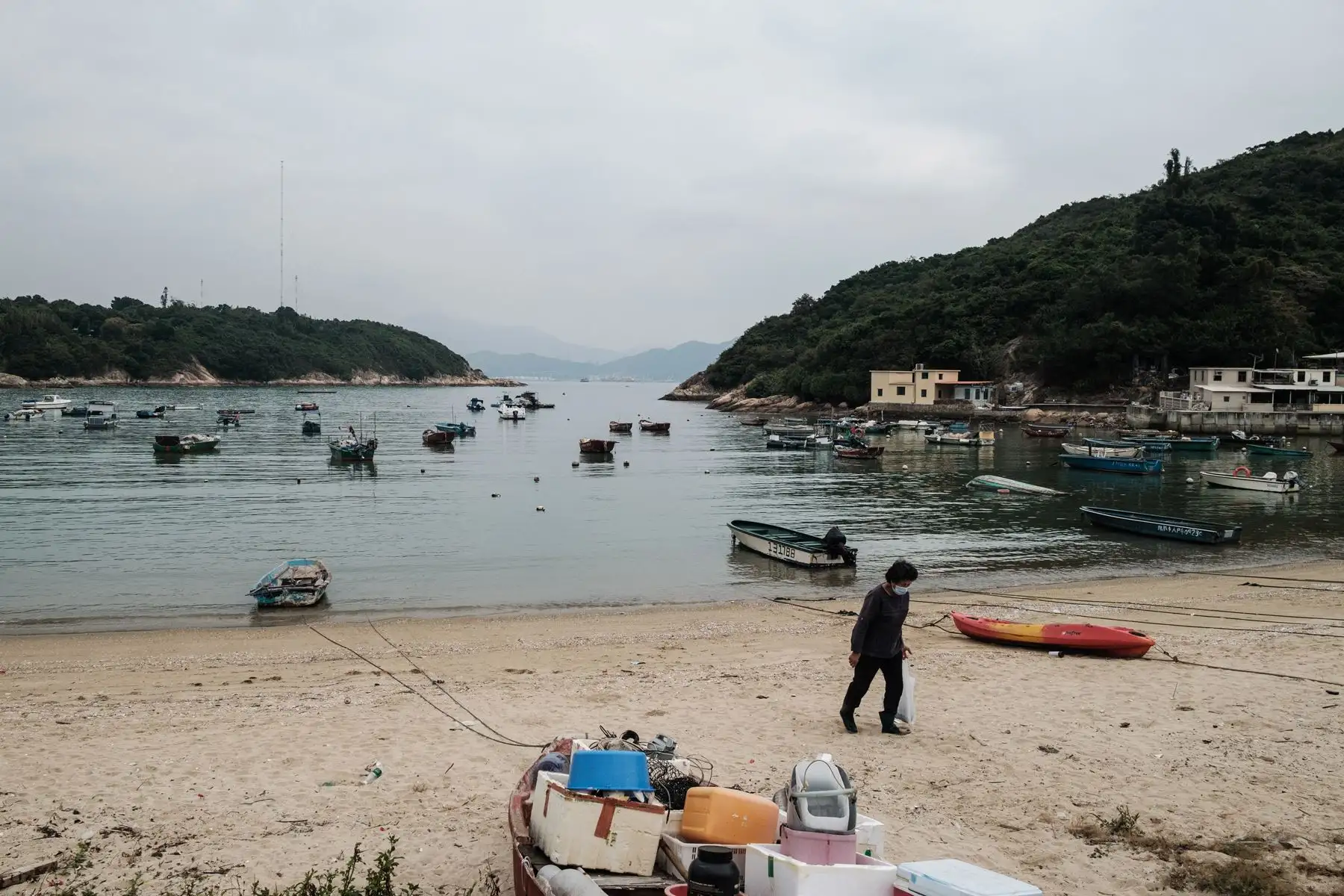 Una mujer lleva su bolsa de pescados después de acercarse a un bote, en una playa de la isla del pueblo pesquero de Peng Chau, en Hong Kong. Foto: AFP