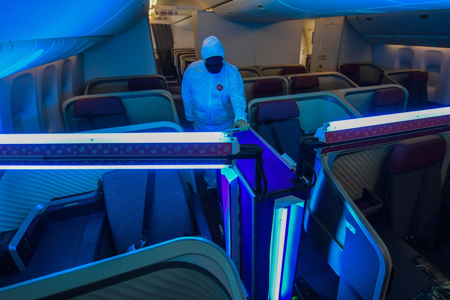 Un empleado de una aerolínea monitorea el funcionamiento de un robot autónomo que utiliza luz ultravioleta tipo C (UV-C) para limpiar el interior de la aeronave, en medio de la pandemia del nuevo coronavirus. Foto: AFP