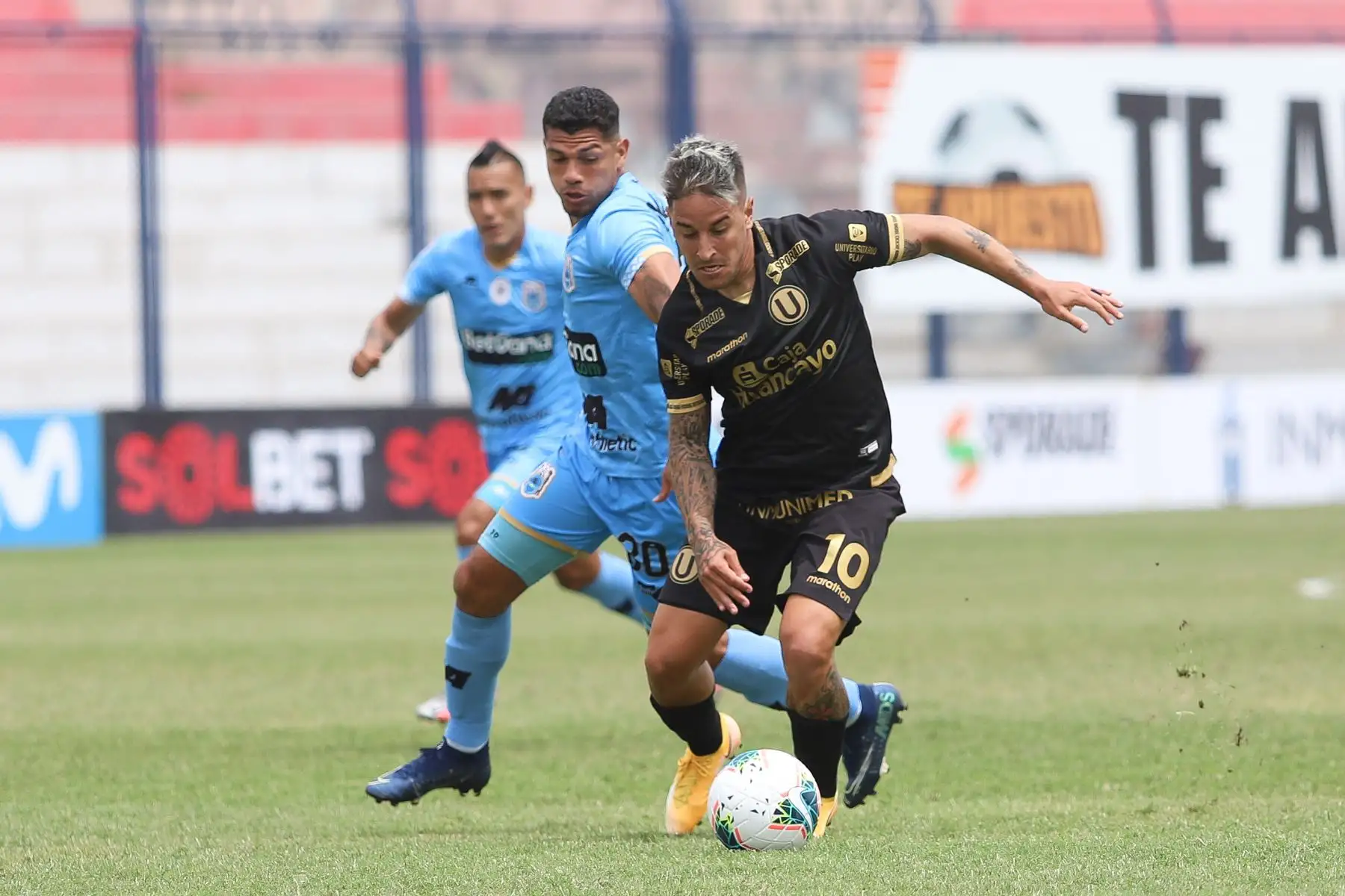 Alejandro Hohberg de Universitario se enfrenta por el balón ante su rival de Binacional durante partido por la última fecha de la fase 2 de la Liga 1, en el estadio Ivan Elías Moreno. Foto: Liga 1