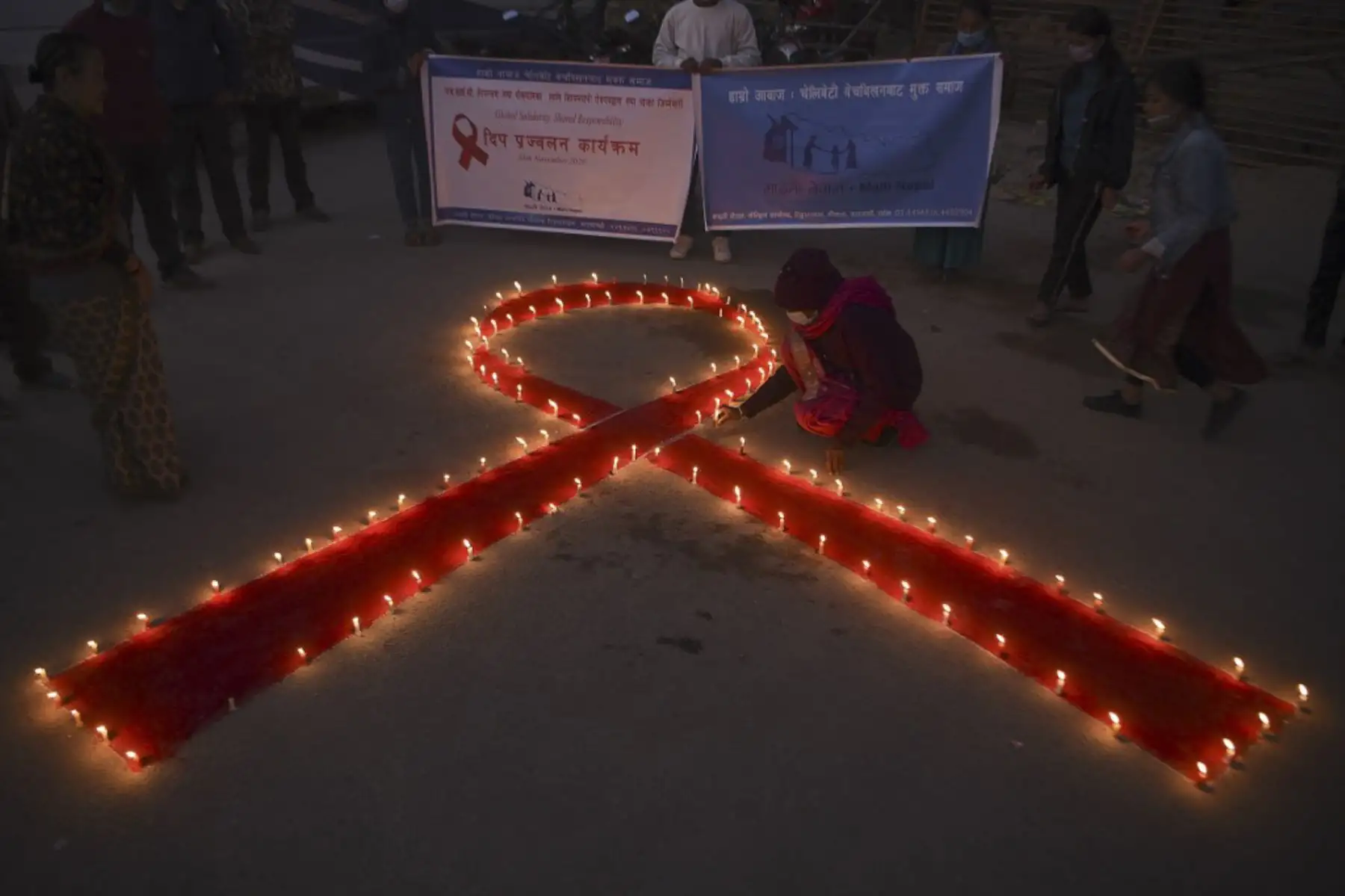 Un voluntario enciende velas en forma de lazo rojo durante un evento de sensibilización en la víspera del Día Mundial del SIDA, en Katmandú. Foto: AFP