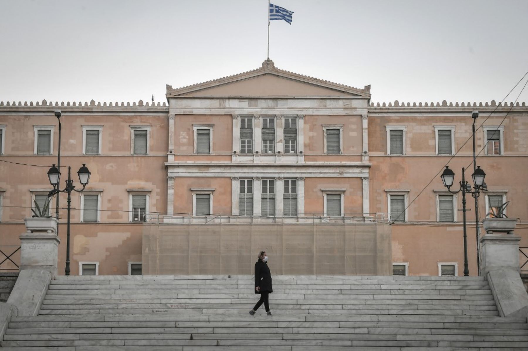 Una mujer camina frente al Parlamento griego en Atenas. Foto: AFP
