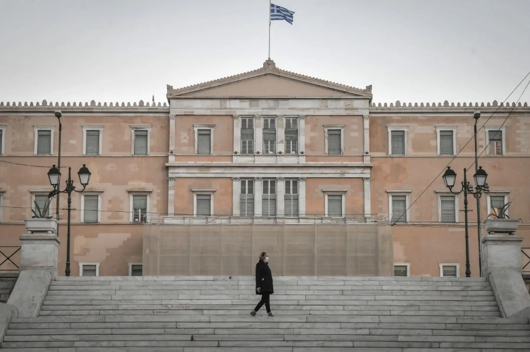 Una mujer camina frente al Parlamento griego en Atenas. Foto: AFP