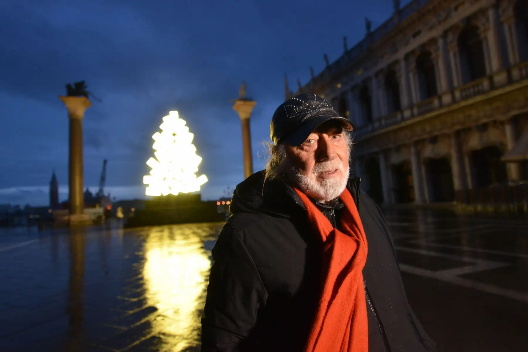 El artista italiano Fabrizio Plessi posa junto a su luminosa instalación montada en las columnas de la Plaza de San Marcos, en Venecia. Foto: AFP