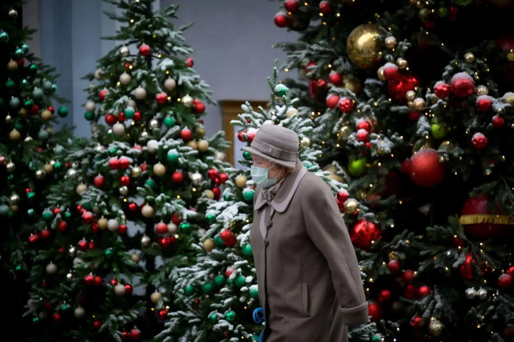 Una mujer que usa una mascarilla para protegerse contra la enfermedad del coronavirus pasa junto a los árboles de Navidad en el centro de Moscú. Foto: AFP