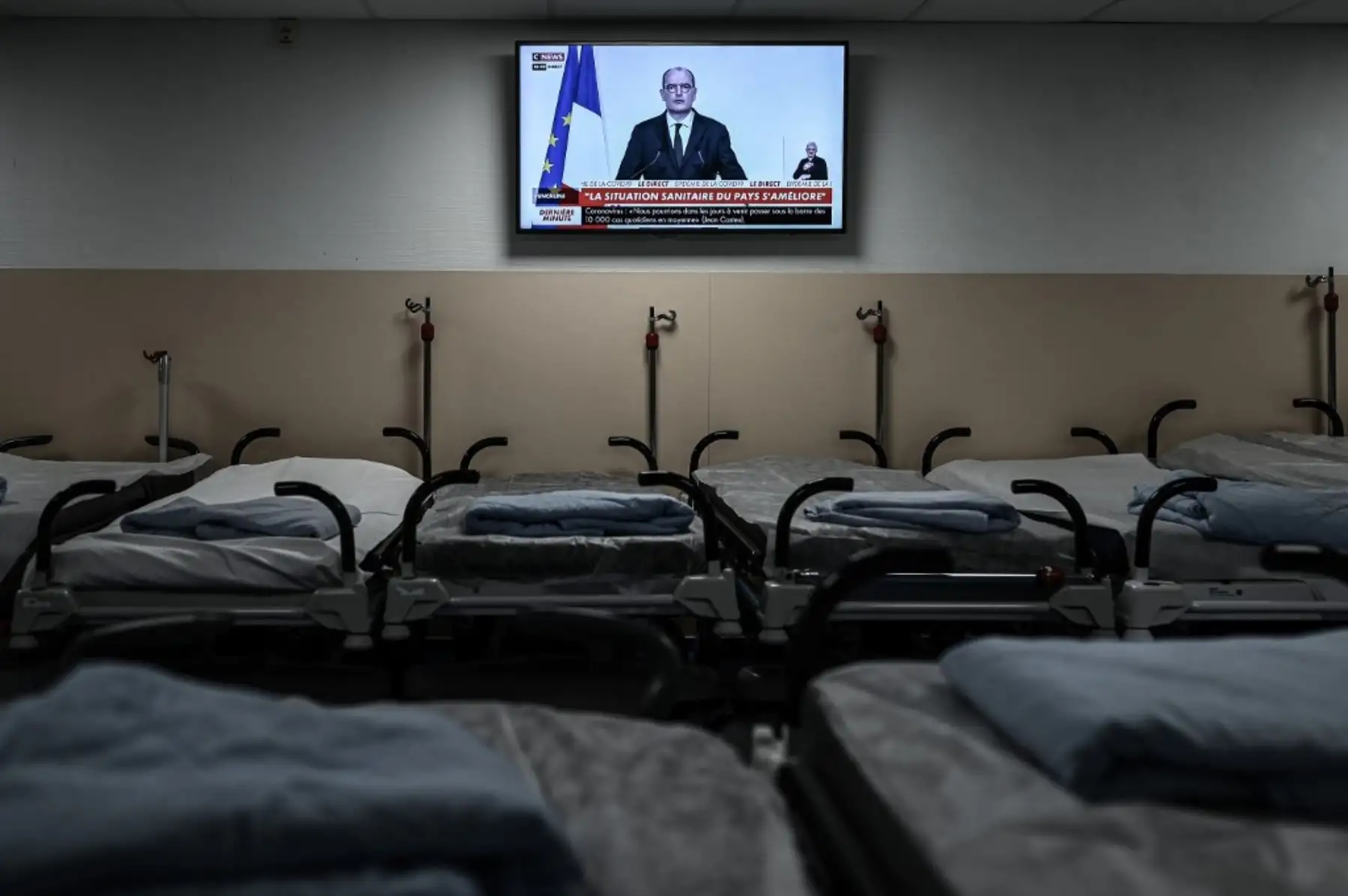 Esta fotografía muestra camas vacías junto a una transmisión de televisión del primer ministro francés mientras habla durante una conferencia de prensa para delinear la estrategia de Francia para el despliegue de futuras vacunas Covid-19 (nuevo coronavirus), en el Polyclinique Jean Villar privado.