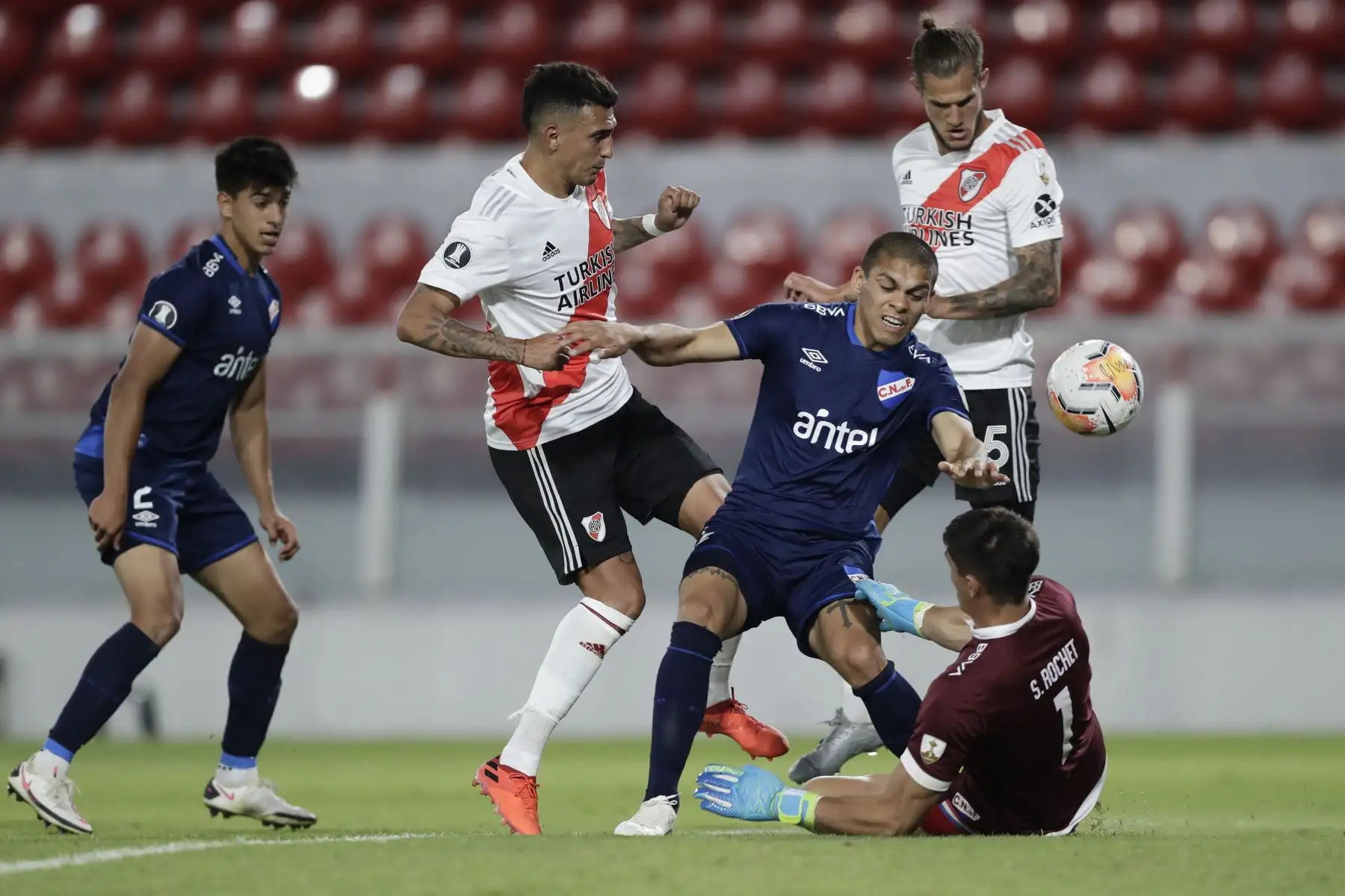 El argentino Matías Suárez de  River Plate  ,  Brian Ocampo , del Nacional de Uruguay y el portero del Nacional de Uruguay Sergio Rochet disputan el balón durante su partido de fútbol de cuartos de final de la Copa Libertadores a puerta cerrada en el estadio Libertadores de América.
Foto: AFP
