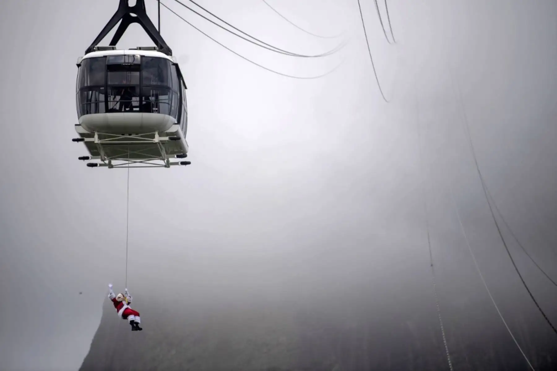 Un hombre disfrazado de Papá Noel, suspendido del teleférico del Pan de Azúcar, saluda a los visitantes a su llegada al cerro Pan de Azúcar, en Río de Janeiro, Brasil. Foto: AFP