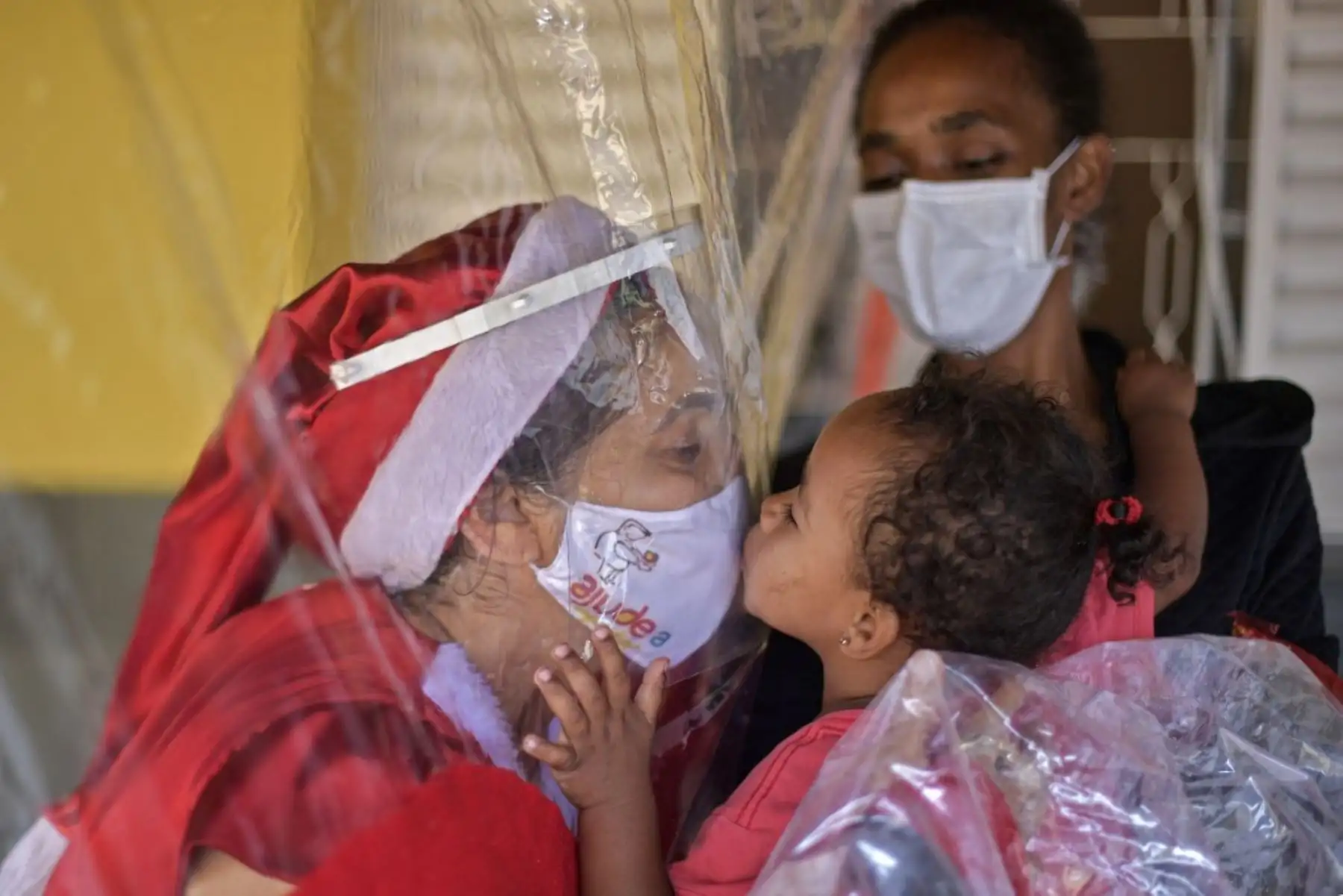 Un niño necesitado besa a la voluntaria Fatima Sanson, vestida como la Sra. Claus, en Belo Horizonte, estado de Minas Gerais, Brasil, el 7 de diciembre de 2020. Foto: AFP