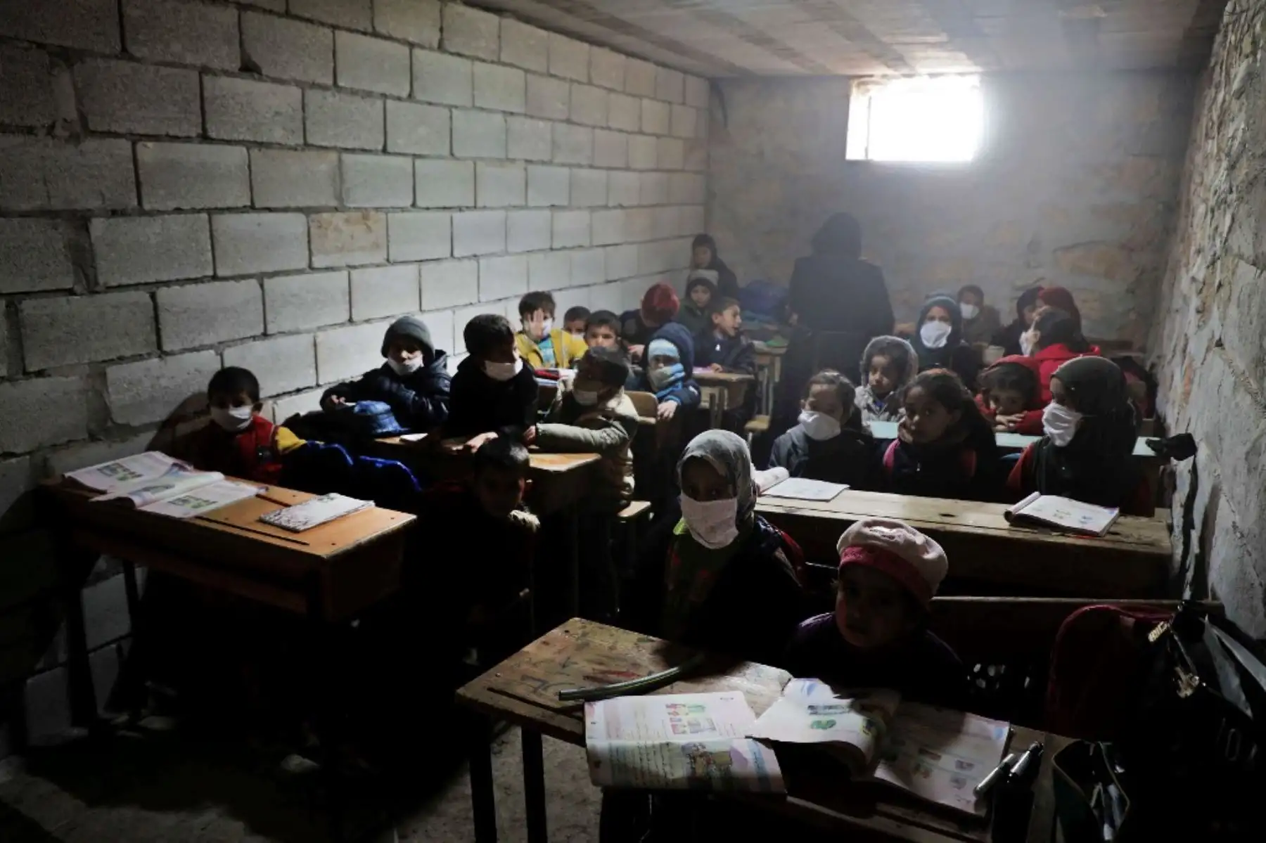 Niños de la escuela sirios con máscaras debido a la pandemia Covid-19, sentados en una escuela improvisada establecida por los lugareños en la aldea de Ma