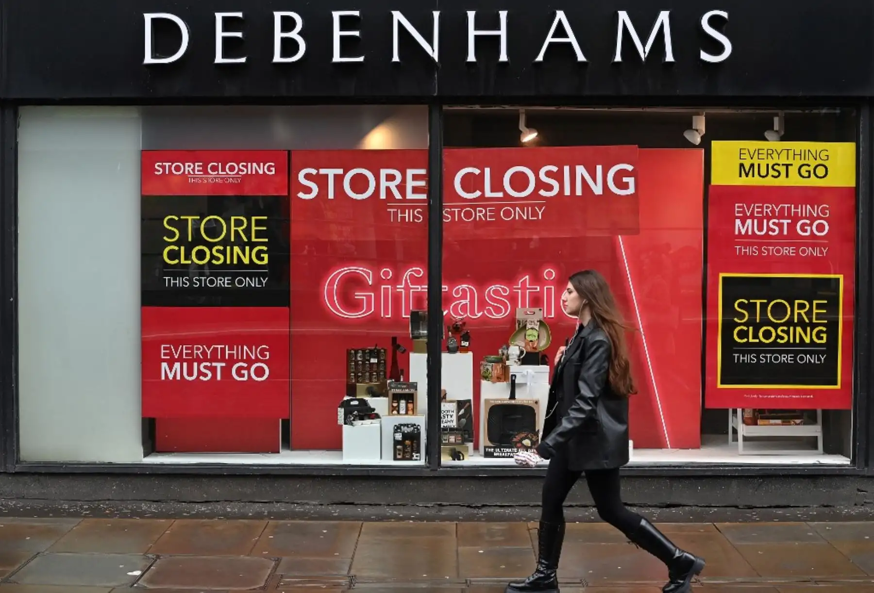 Un peatón pasa junto a los letreros de "Cierre de tienda" en el escaparate de una tienda Debenhams en Manchester, en el norte de Inglaterra. Foto: AFP