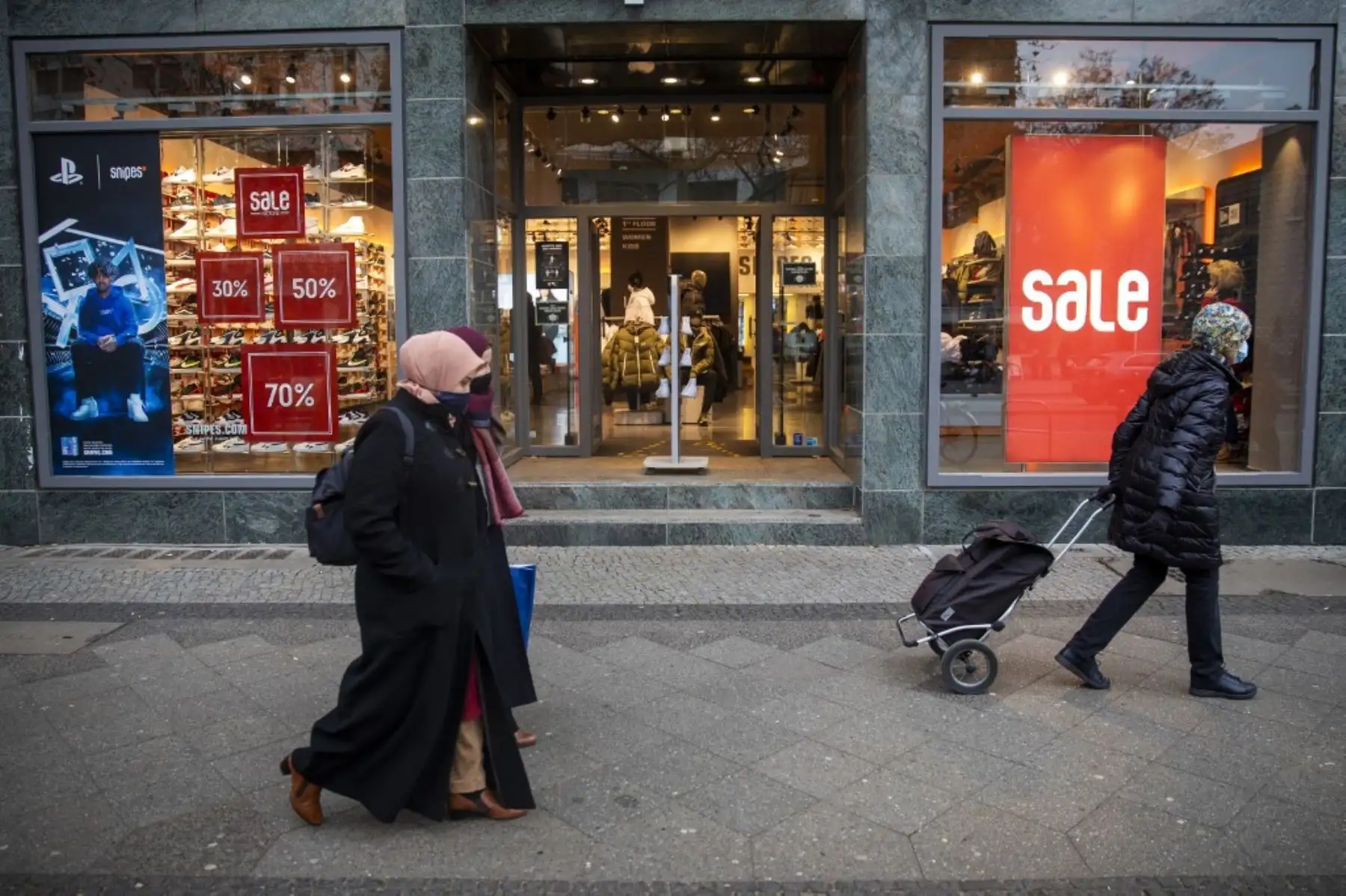 Los compradores pasan junto a carteles de venta en una tienda de zapatos en la calle Schlossstrasse en Berlín el 11 de diciembre de 2020. Foto: AFP