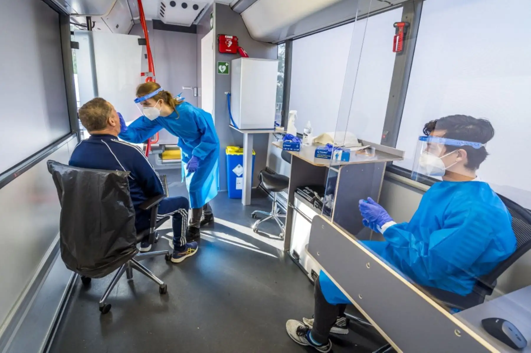 Un trabajador de la salud realiza una prueba de hisopo en un hombre en un autobús convertido en un laboratorio móvil de pruebas de covid-19. Foto: AFP