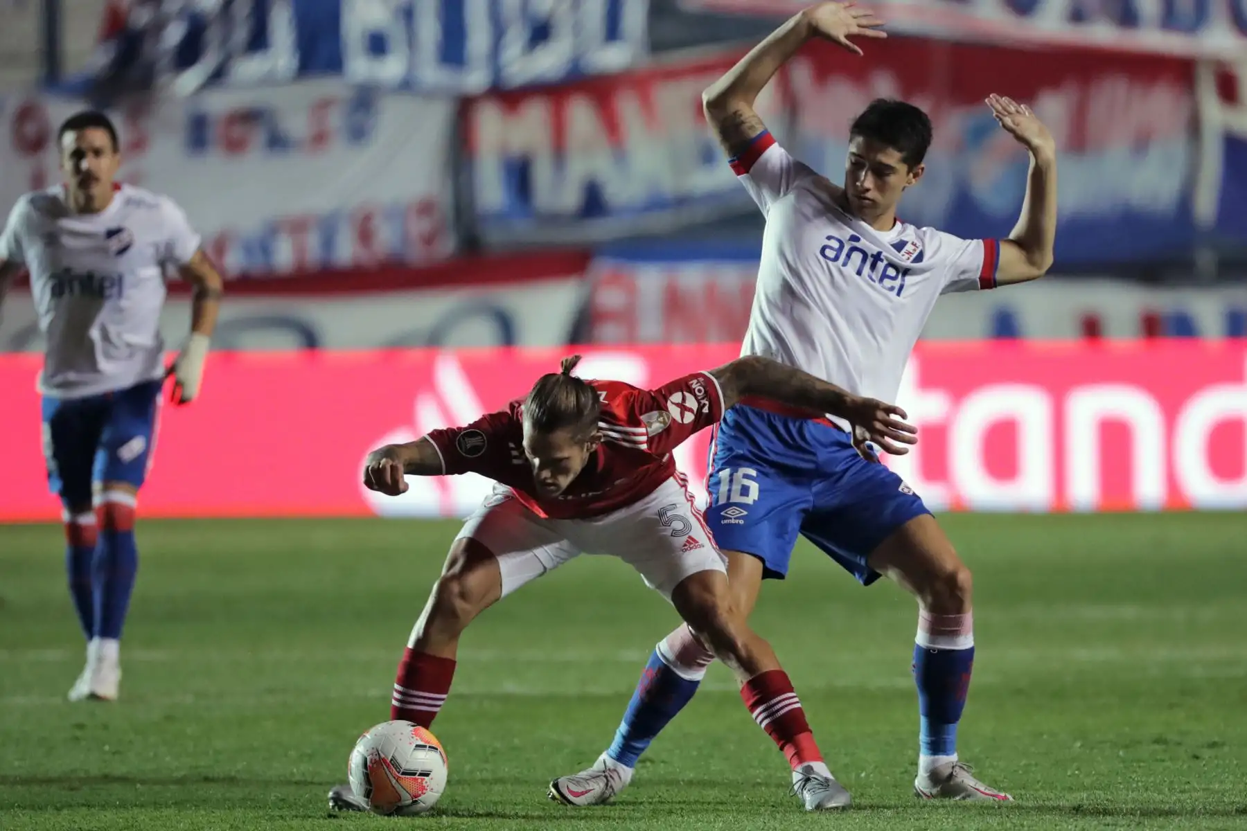 El argentino River Plate Bruno Zuculini  y el uruguayo Nacional Emiliano Martínez compiten por el balón durante su partido de fútbol de cuartos de final de la Copa Libertadores a puerta cerrada en el estadio Gran Parque Central de Montevideo.
Foto: AFP