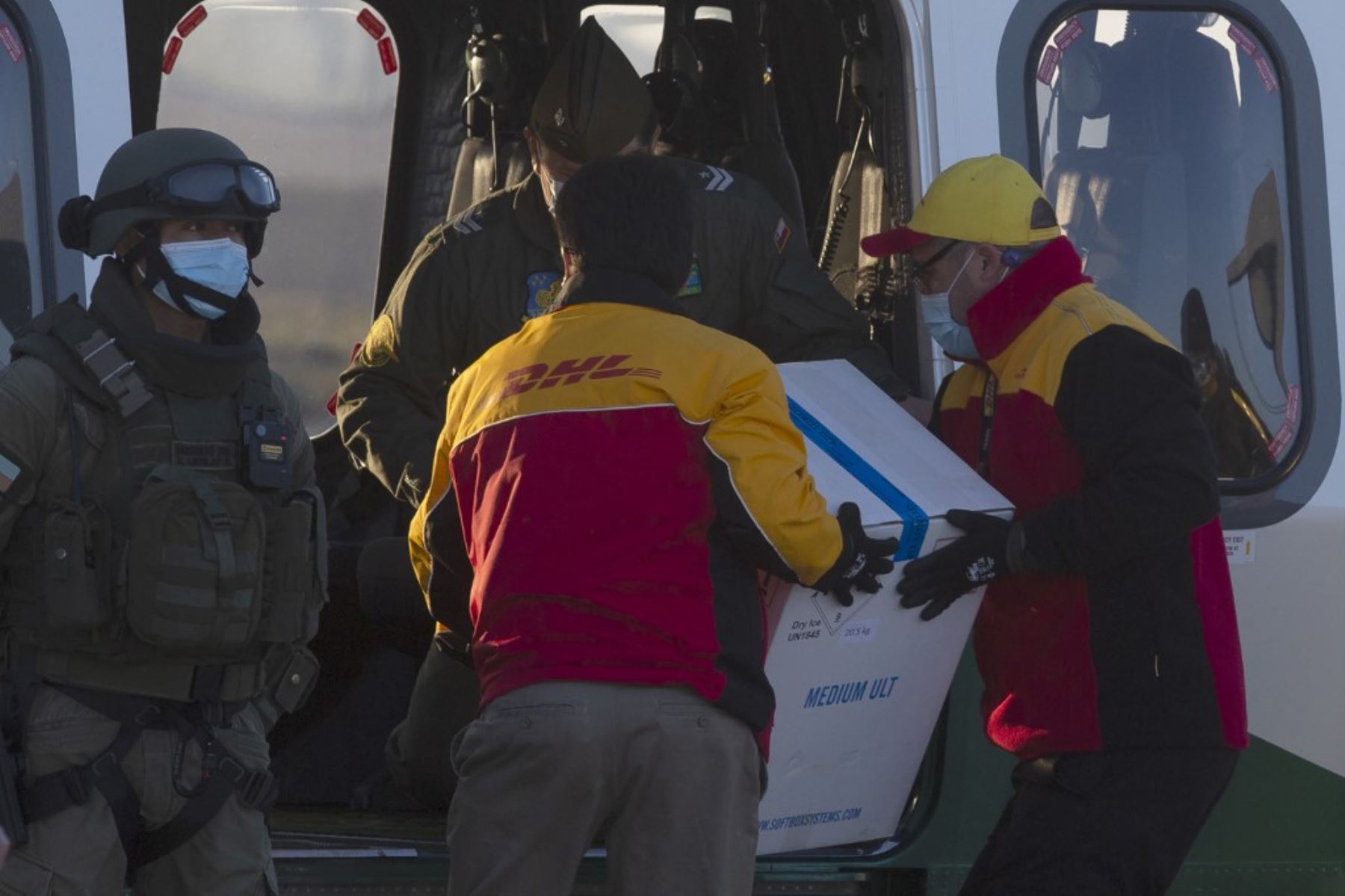 Los trabajadores llevan una caja que contiene la vacuna contra el coronavirus Pfizer-BioNTech covid-19 a un helicóptero para su distribución en el aeropuerto internacional de Santiago de Chile. Foto: AFP