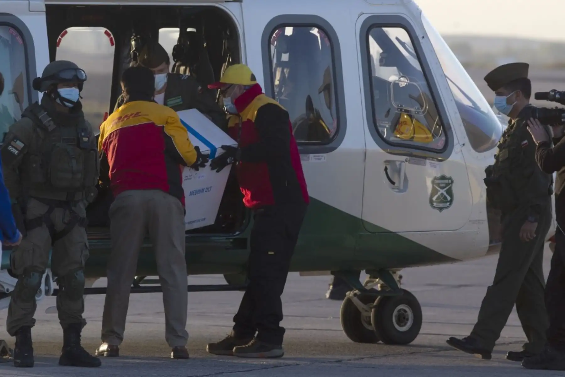 Los trabajadores llevan una caja que contiene la vacuna contra el coronavirus Pfizer-BioNTech covid-19 a un helicóptero para su distribución en el aeropuerto internacional de Santiago de Chile. Foto: AFP