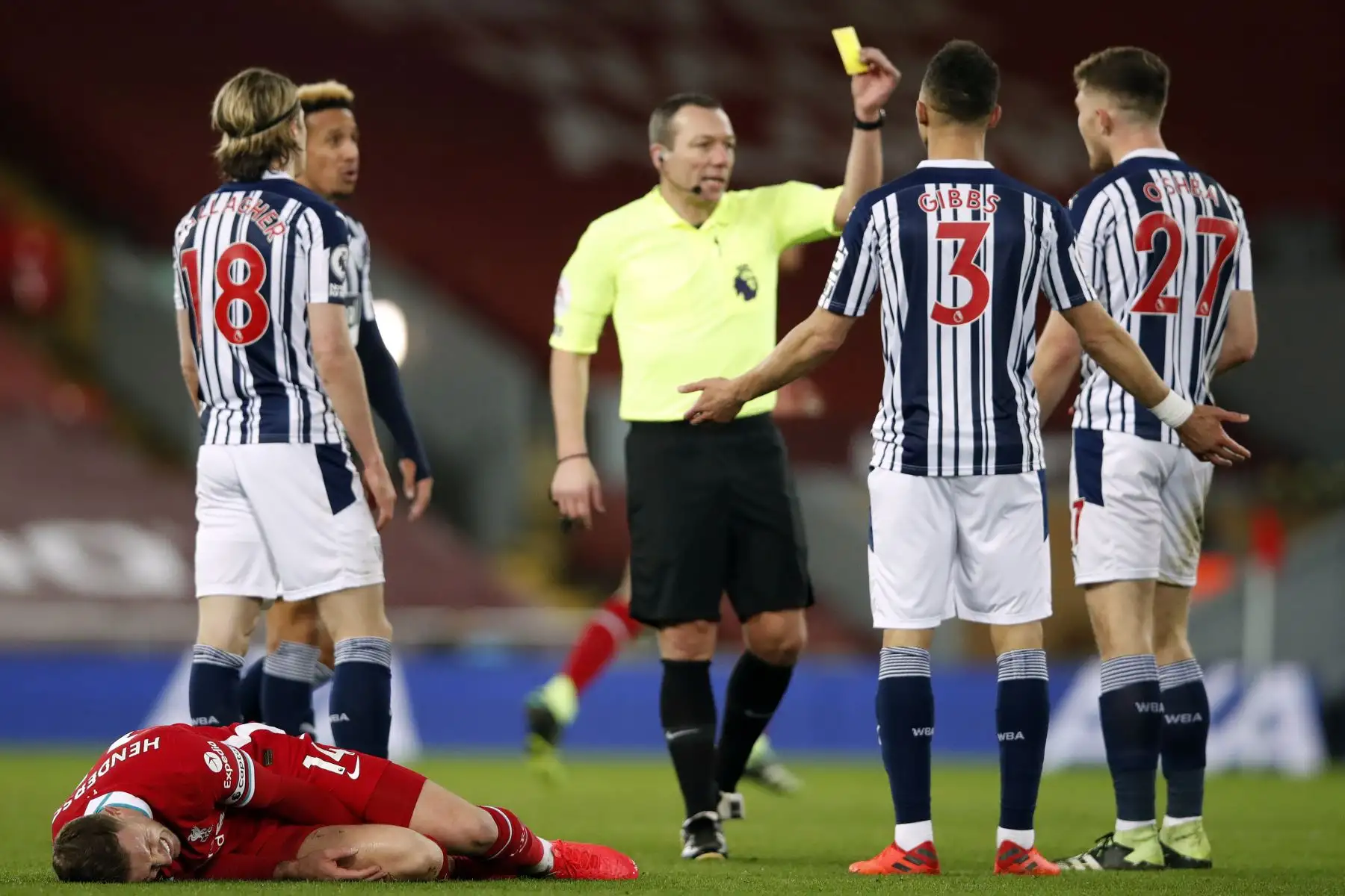El centrocampista inglés del Liverpool Jordan Henderson yace lesionado mientras el defensor irlandés del West Bromwich Albion, Dara O