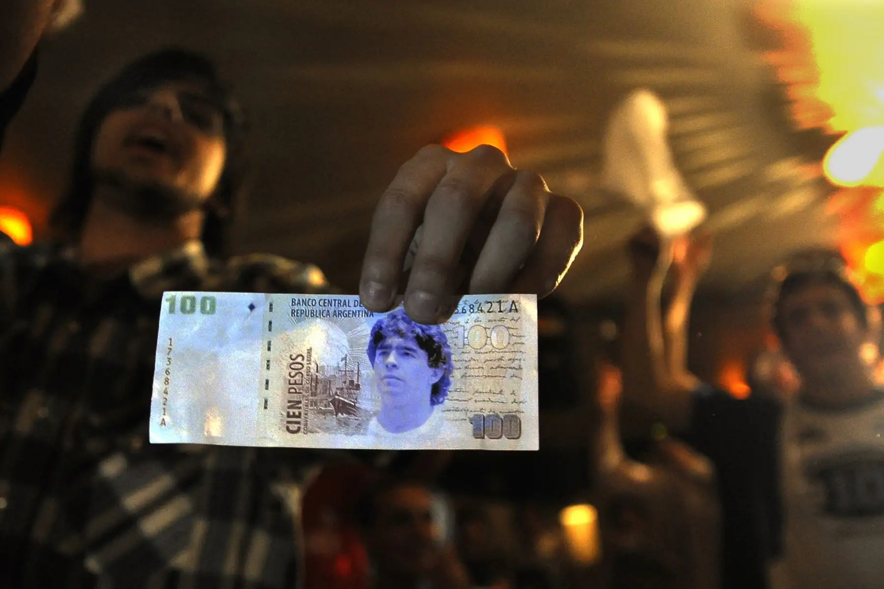 En esta foto de archivo tomada el 30 de octubre de 2008, un miembro de la Iglesia Maradoniana La mano de Dios, una religión dedicada al mejor futbolista argentino Diego Maradona, muestra un "billete" de cien pesos durante su celebración navideña la noche. Foto: AFP