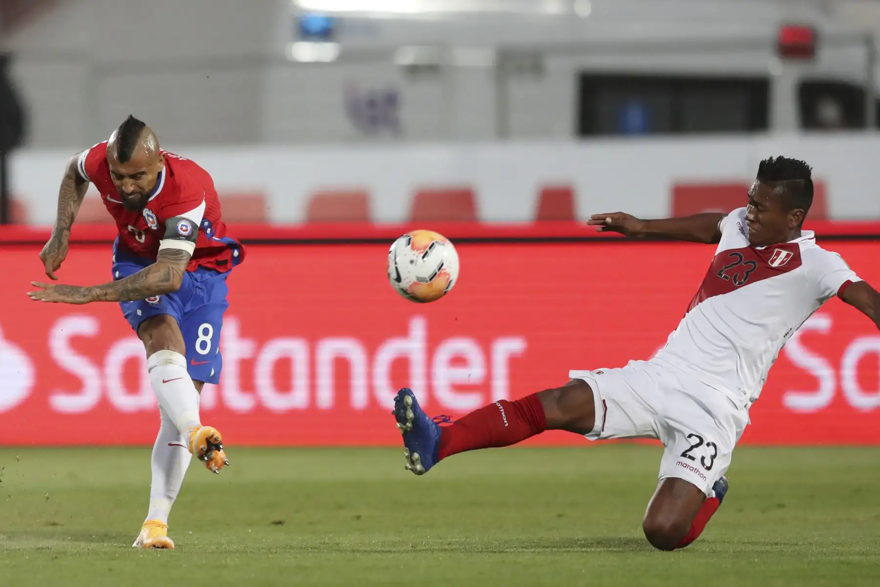 El chileno Arturo Vidal golpea el balón sobre el peruano Pedro Aquino para anotar durante su partido de fútbol a puertas cerradas clasificatorio sudamericano para la Copa Mundial de la FIFA 2022 en el Estadio Nacional de Santiago, el 13 de noviembre de 2020.
Foto: AFP