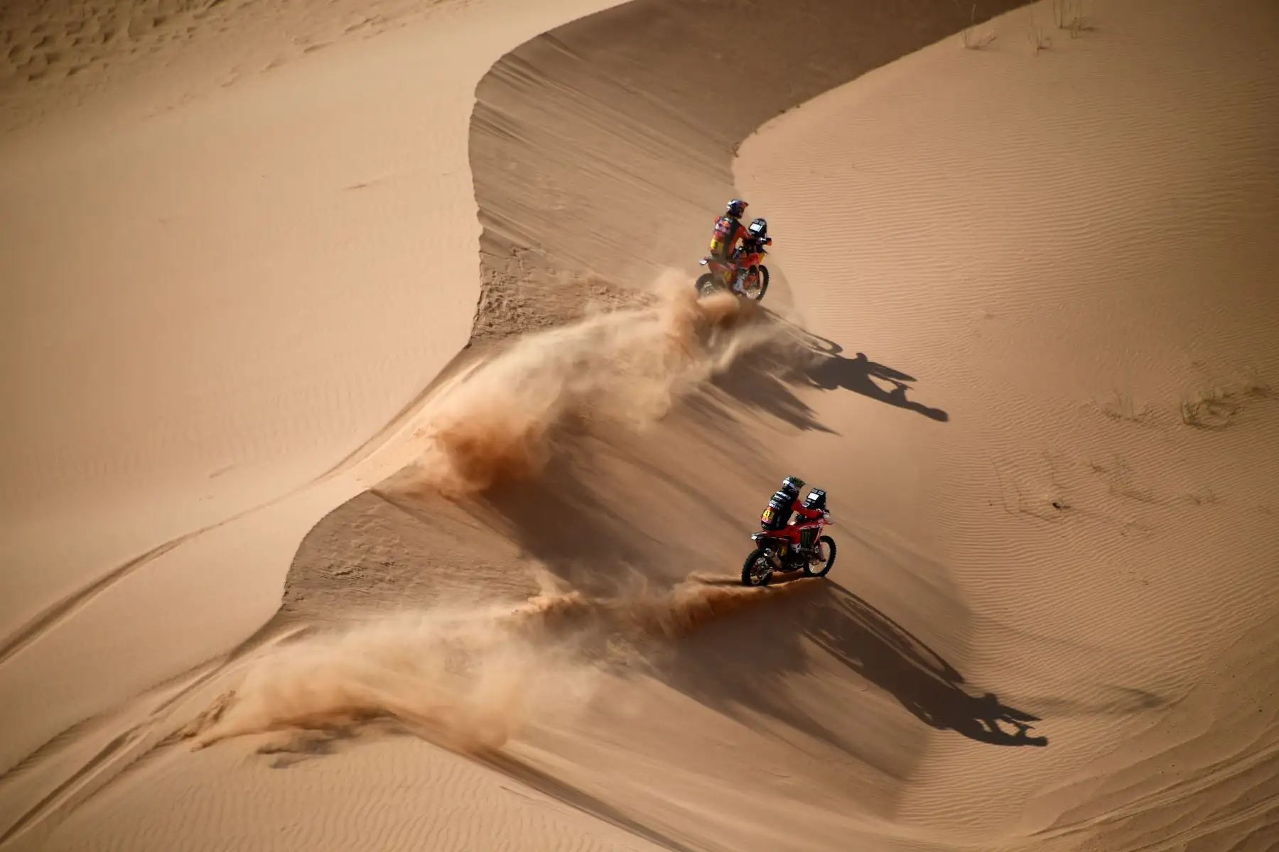 El motociclista australiano Toby Price y el ciclista argentino Kevin Benavides compiten durante la etapa 4 del Rally Dakar 2021 entre Wadi Ad-Dawasir y la capital de Arabia Saudita. Foto: AFP