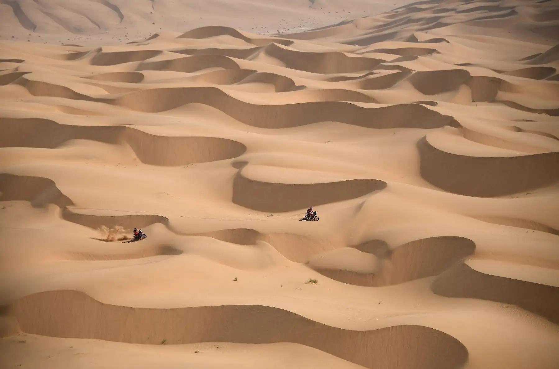 El motociclista australiano Toby Price y el ciclista argentino Kevin Benavides compiten durante la etapa 4 del Rally Dakar 2021 entre Wadi Ad-Dawasir y la capital de Arabia Saudita. Foto: AFP