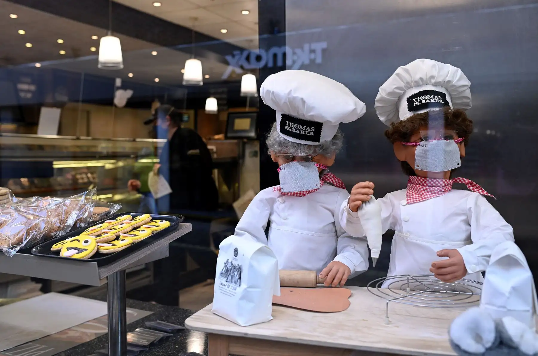 En la ventana de una panadería se muestran títeres que llevan cubiertas faciales, ofreciendo un servicio de comida para llevar en York, noroeste de Inglaterra. Foto: AFP