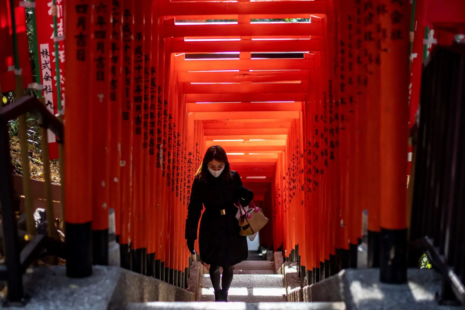 Una mujer con una máscara facial camina debajo de una hilera de puertas en el Santuario Hie en Tokio, ya que se esperaba que el gobierno de Japón declarara un estado de emergencia por coronavirus. Foto: AFP