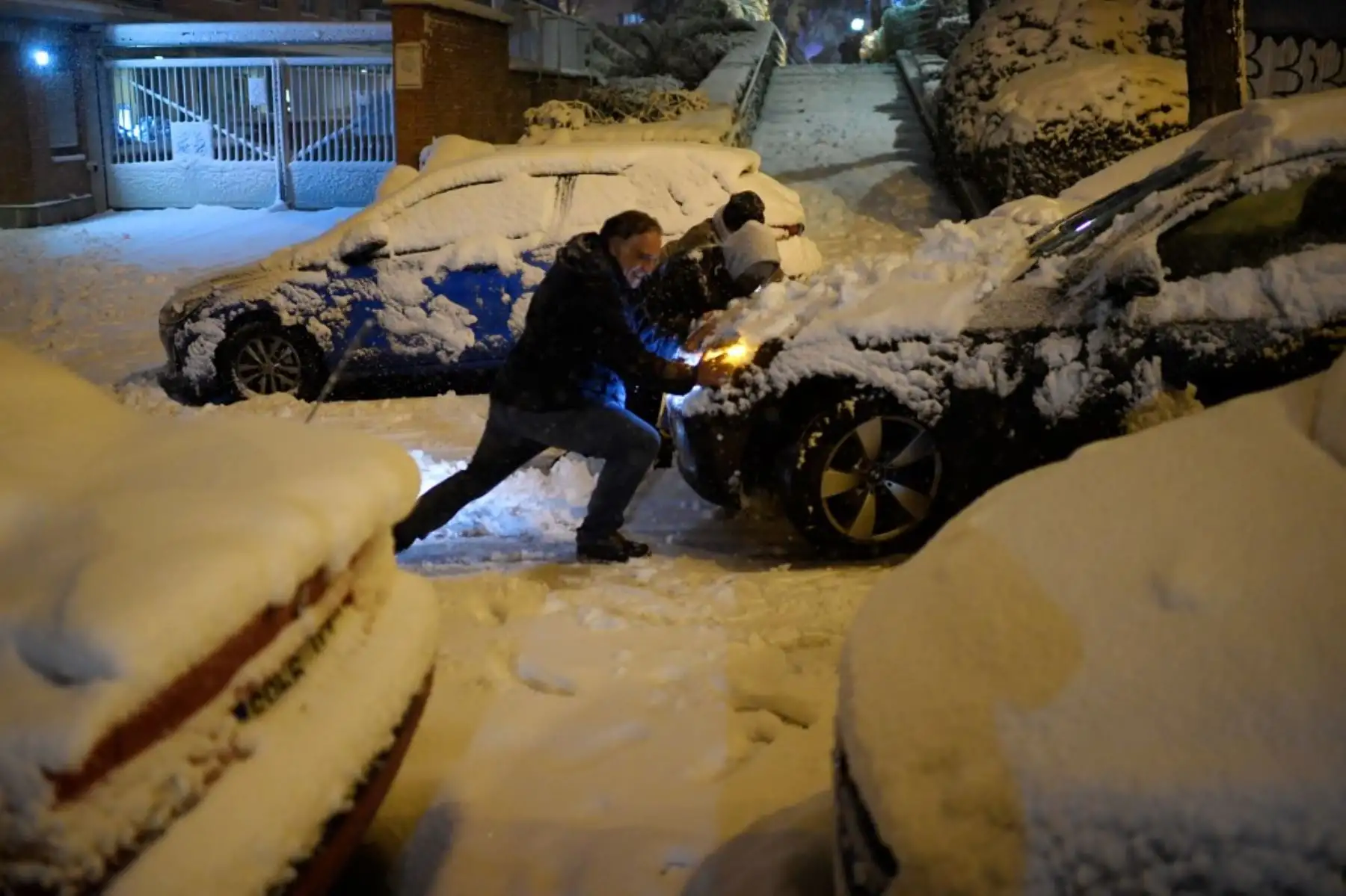 La gente empuja un coche atascado en la nieve en Madrid el 8 de enero de 2021. Foto: AFP