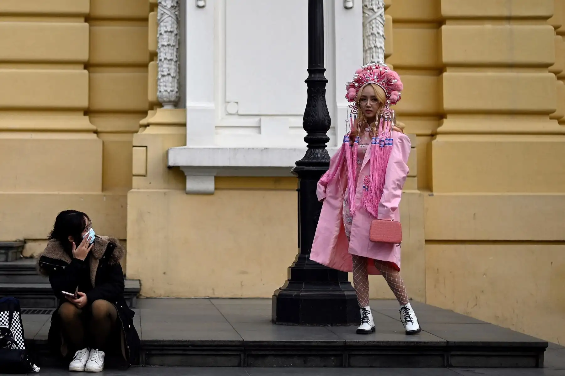 Una mujer observa a otra posando para fotografías fuera de la Ópera de Hanói. Foto: AFP