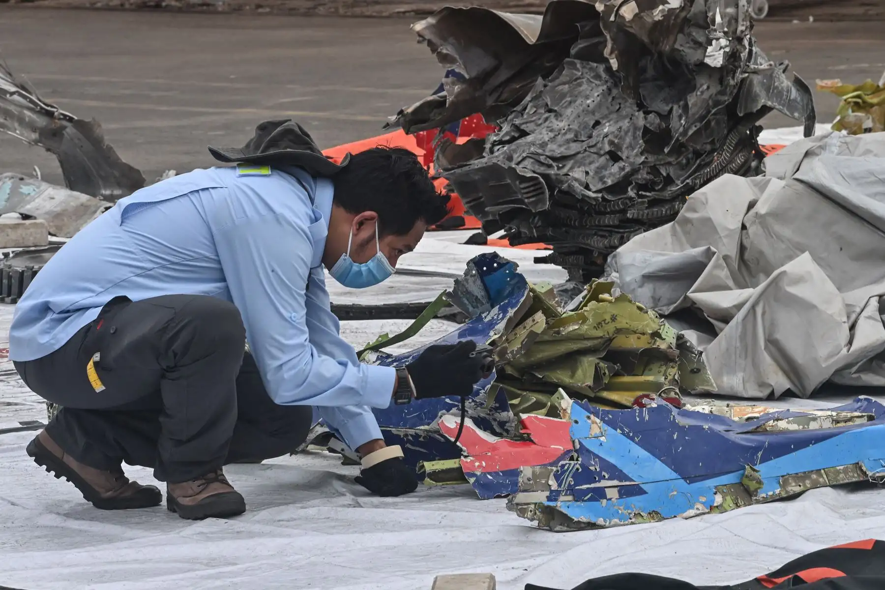 Un miembro del Comité Nacional de Seguridad del Transporte (KNKT) inspecciona los restos del vuelo SJ182 de Sriwijaya Air en el puerto de Tanjung Priok. Foto: AFP
