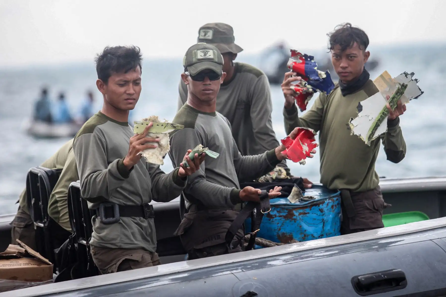 Buzos de la Armada de Indonesia muestran piezas de escombros recuperados frente a la costa norte de Yakarta. Foto: AFP