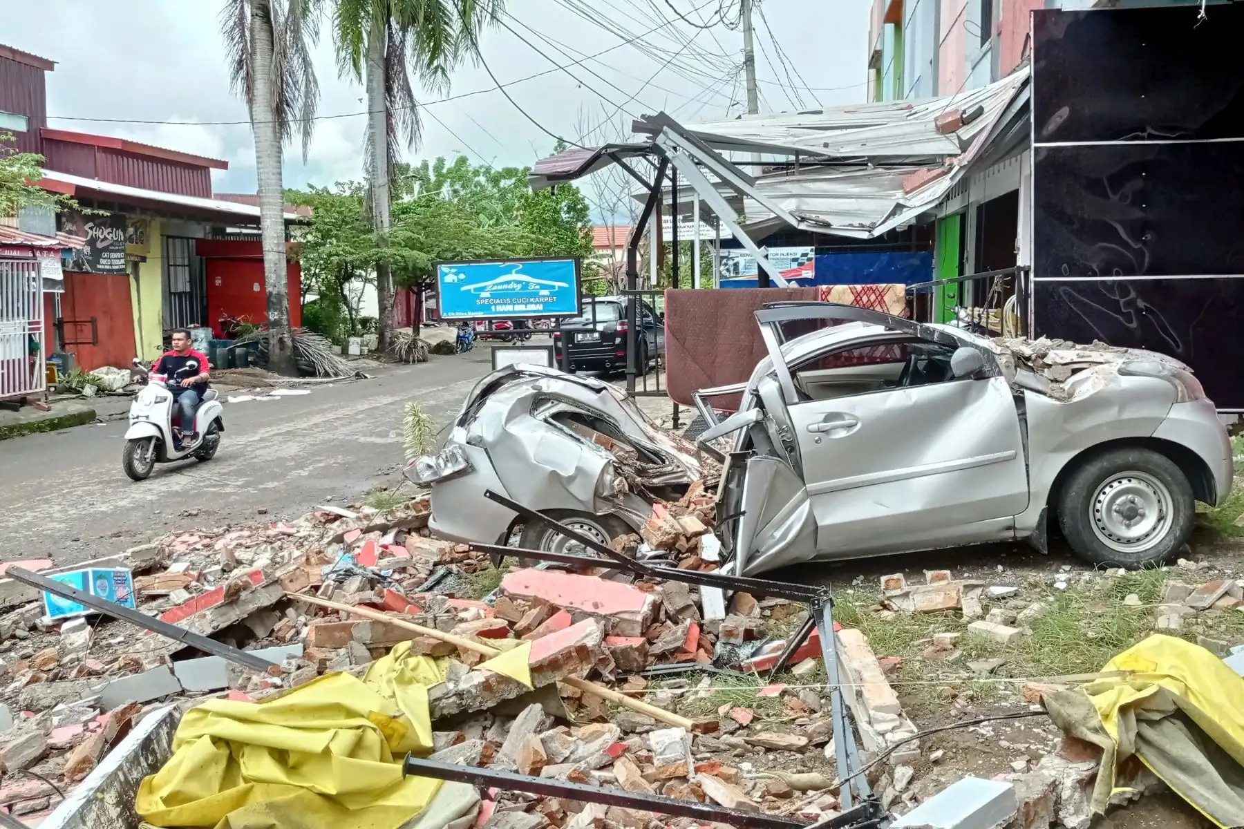 Un automóvil destruido se encuentra entre los escombros al costado de una calle en Mamuju, después de que un terremoto de magnitud 6.2 sacudiera la isla de Sulawesi en Indonesia. Foto: AFP