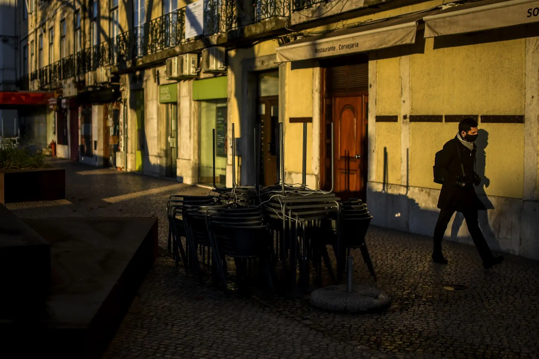 Un hombre pasa frente a un restaurante cerrado en Lisboa,  Portugal entró en un nuevo bloqueo por un aumento en los casos de coronavirus. El nuevo coronavirus ha matado al menos a 1.994.833 personas. Foto: AFP