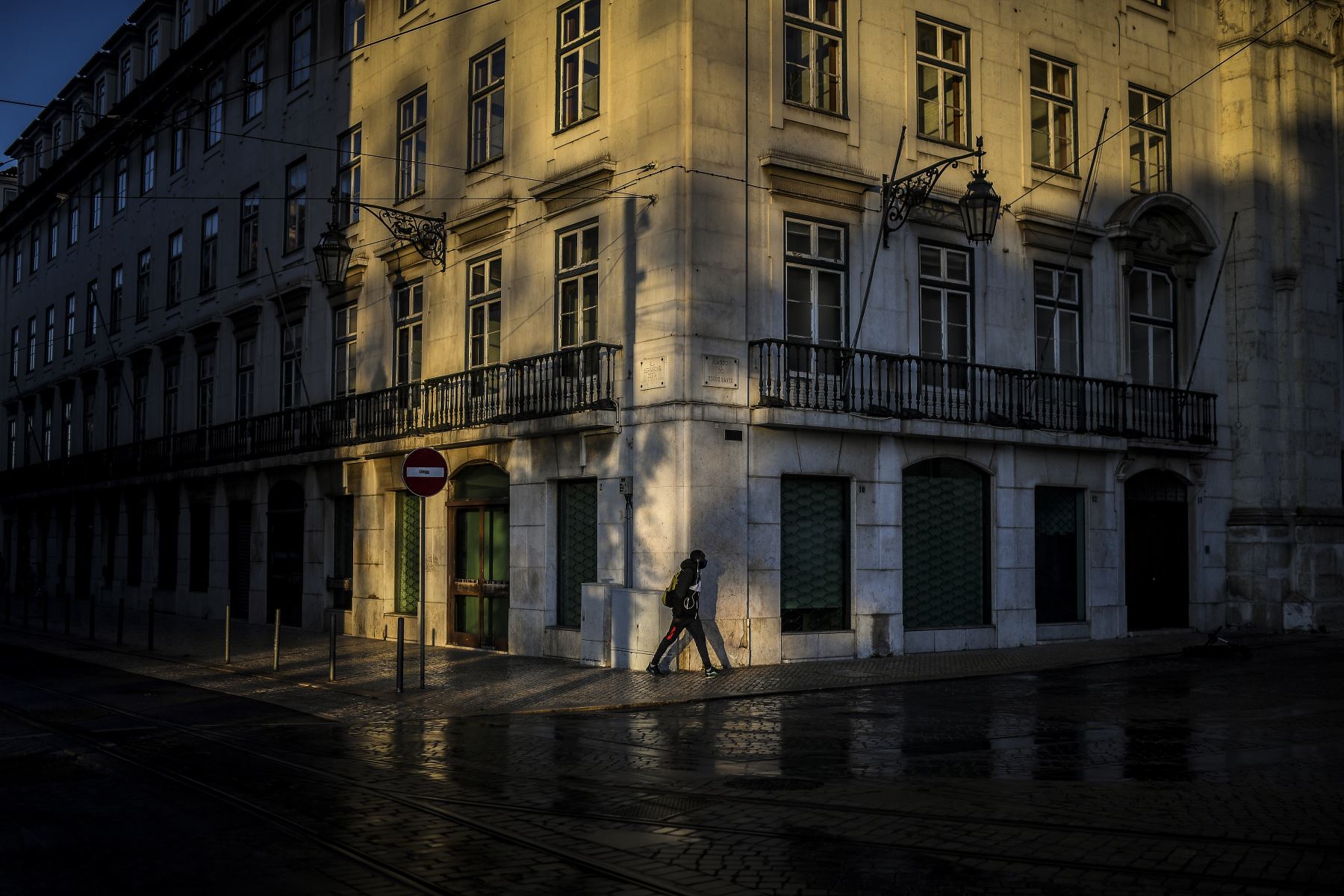 Un hombre camina por las calles vacías de Lisboa, Portugal entró en un nuevo bloqueo por un aumento en los casos de coronavirus. El nuevo coronavirus ha matado al menos a 1,994,833 personas. Foto: AFP