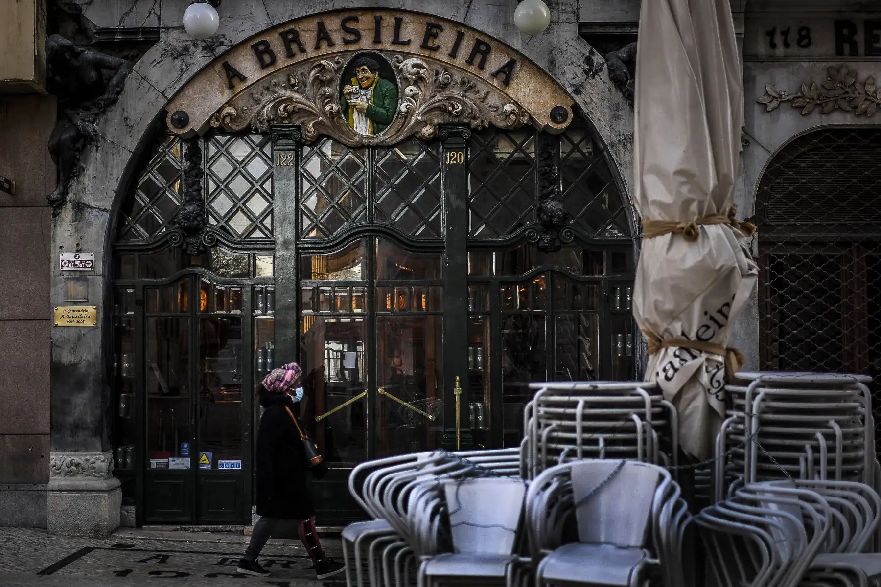 Una mujer pasa frente a la cafetería "A Brasileira" en Lisboa Portugal, que  ingresó a un nuevo bloqueo por un aumento en los casos de coronavirus. El nuevo coronavirus ha matado al menos a 1.994.833 personas. Foto: AFP