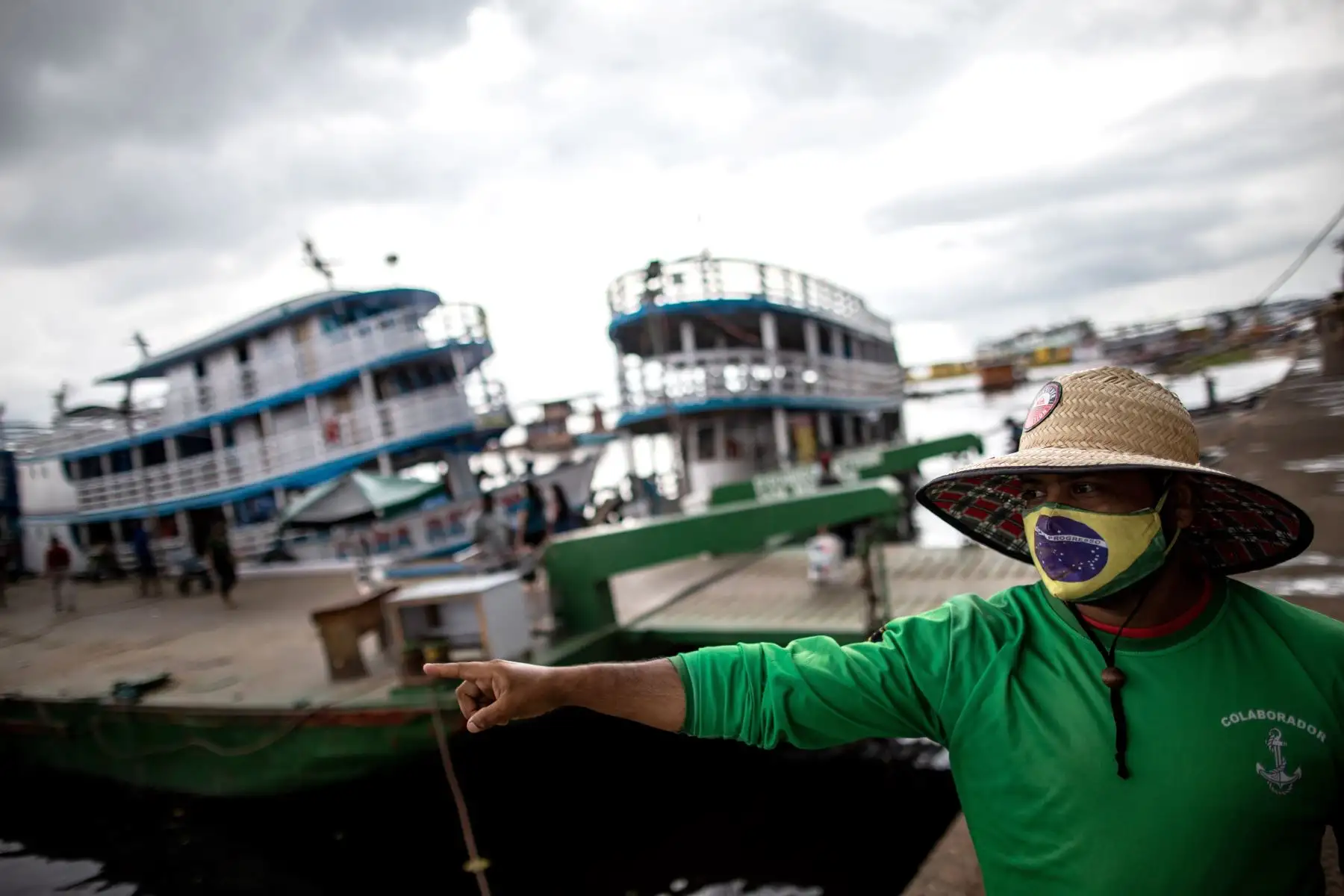 Un hombre con tapabocas de diseño de la bandera brasileña señala hacia el río Amazonas hoy, en Manaos, Brasil. La nueva variante de la covid detectada en la Amazonía brasileña  no solo llevó a que Reino Unido vetara los vuelos desde Portugal y Suramérica sino también a algunas regiones de Brasil.
Foto: EFE