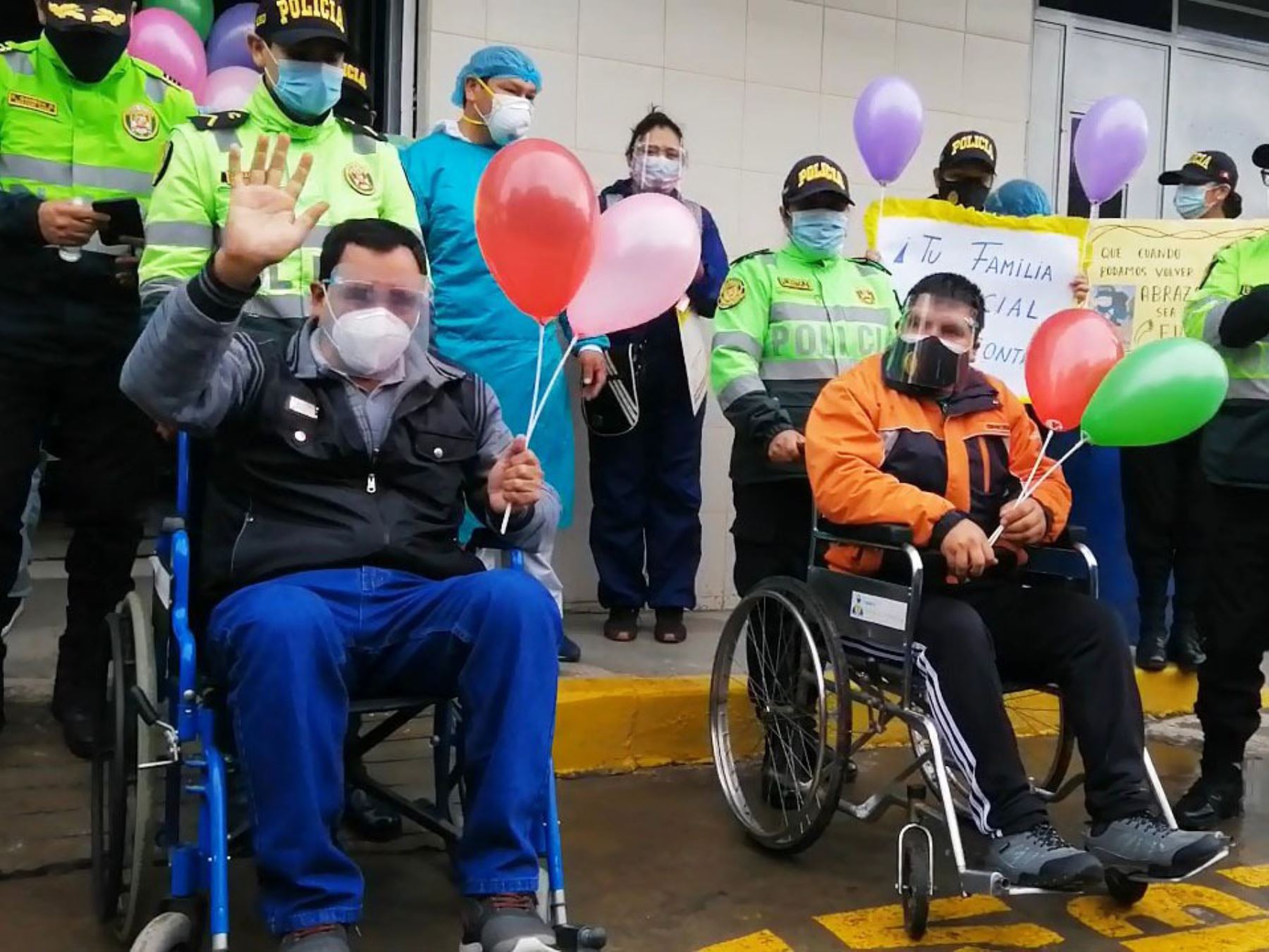 Con globos y aplausos, miembros de la Policía Nacional reciben a dos de sus colegas (en sillas de ruedas) que vencieron al covid-19.